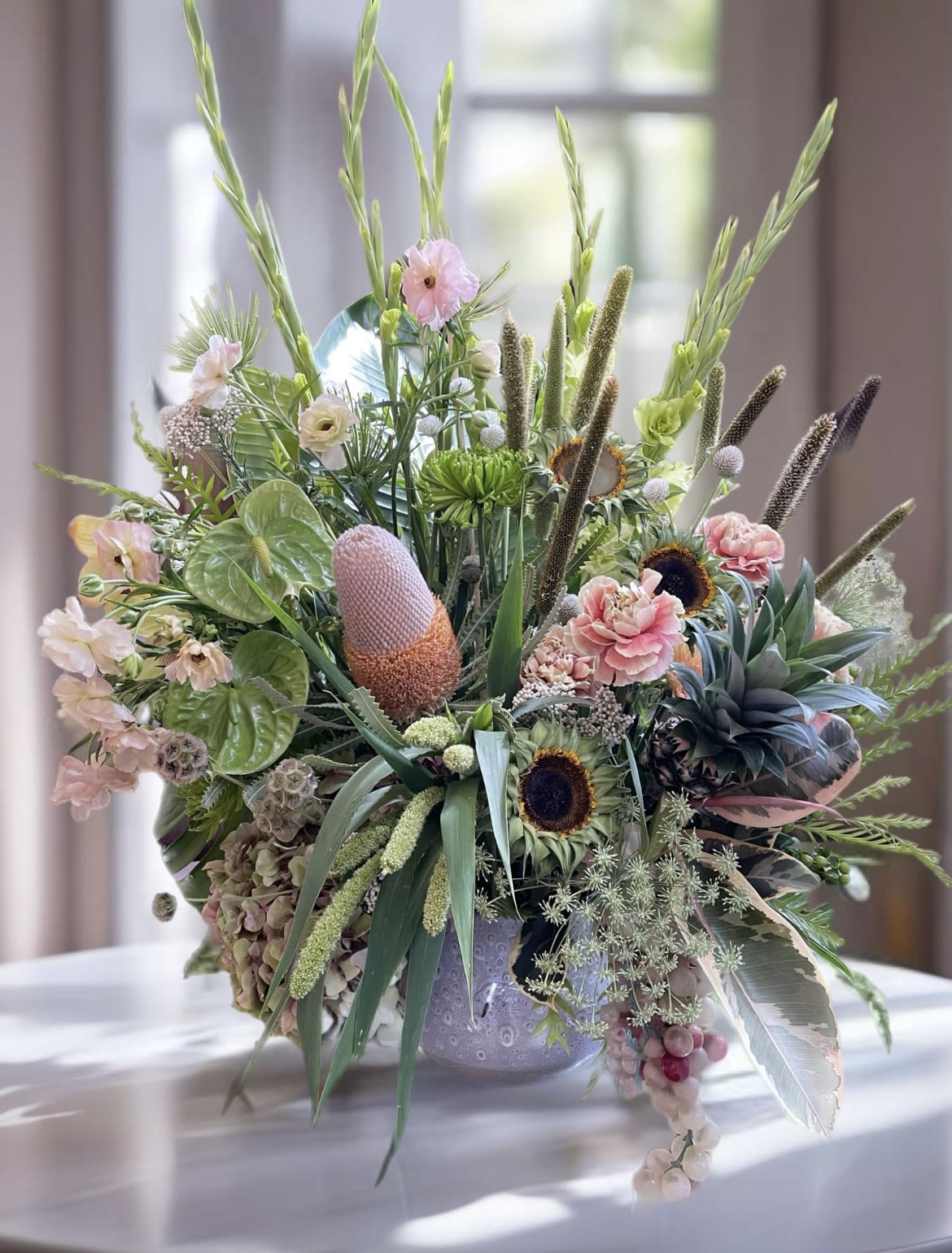 Large mixed floral arrangement in a decorative vase with pink and green blooms