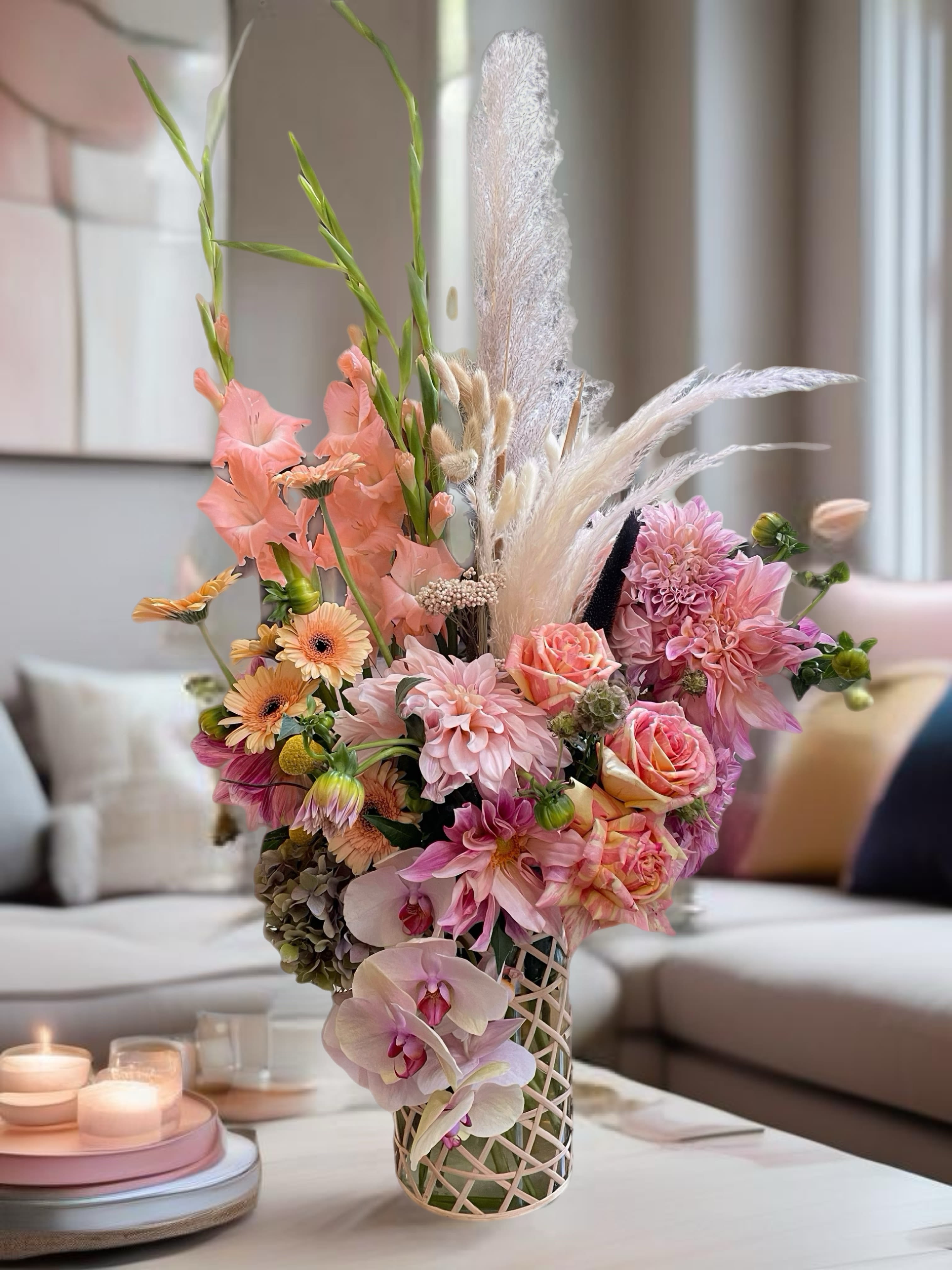 Pastel floral arrangement with orchids, roses, and dahlias in a lattice vase