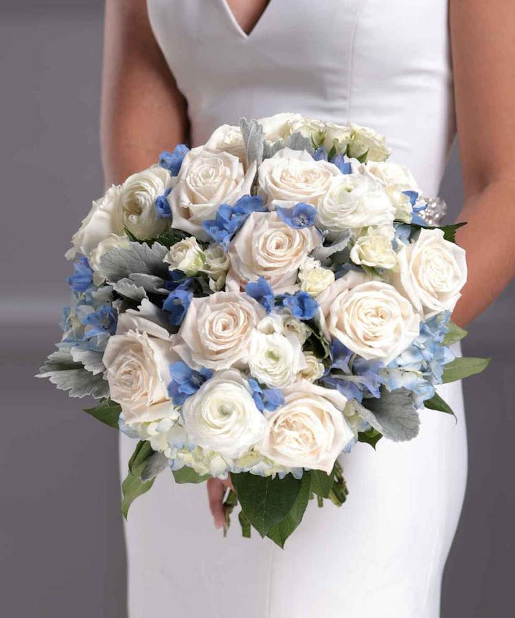 Bride holding a bouquet of white roses and blue flowers