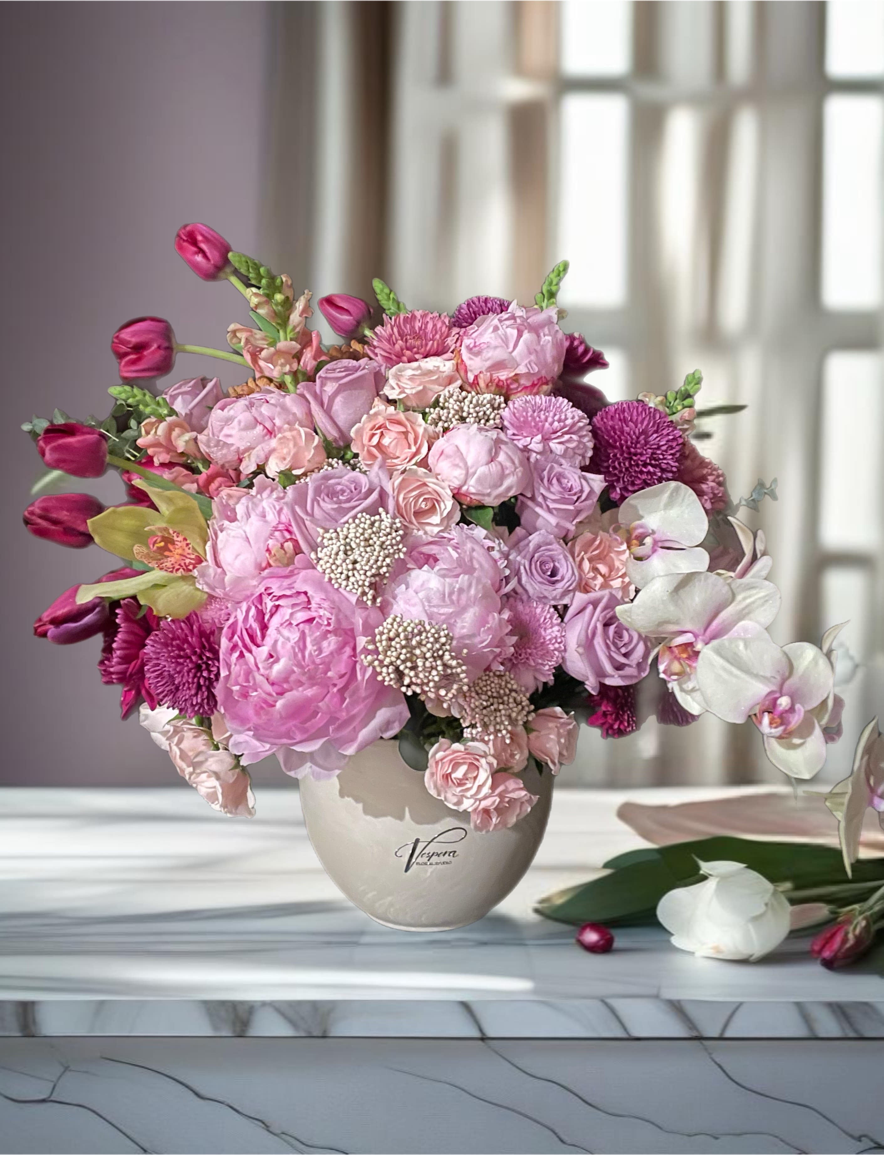 Pink and lavender flower arrangement in a beige vase