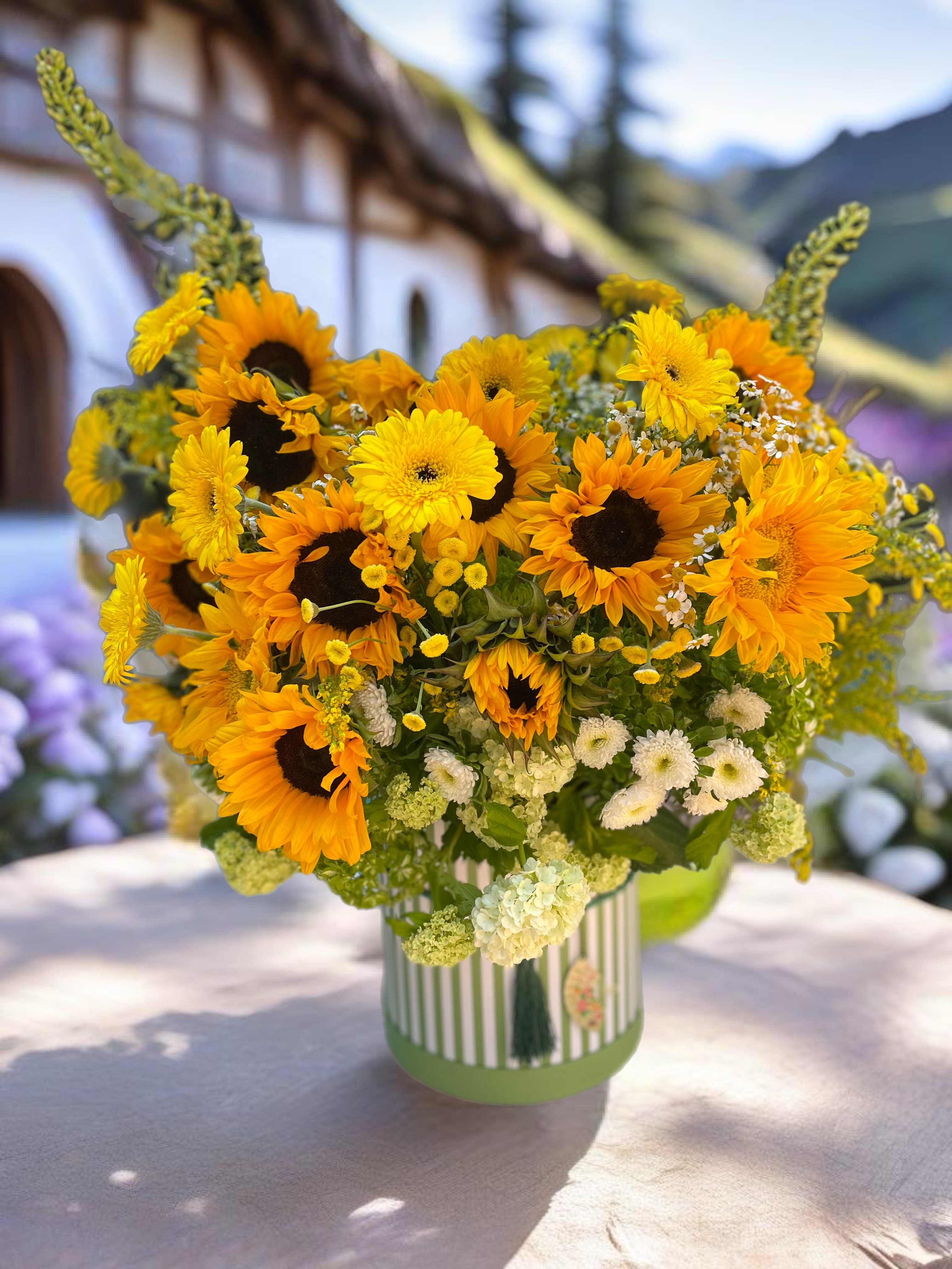 Bouquet of sunflowers and yellow daisies in a striped vase