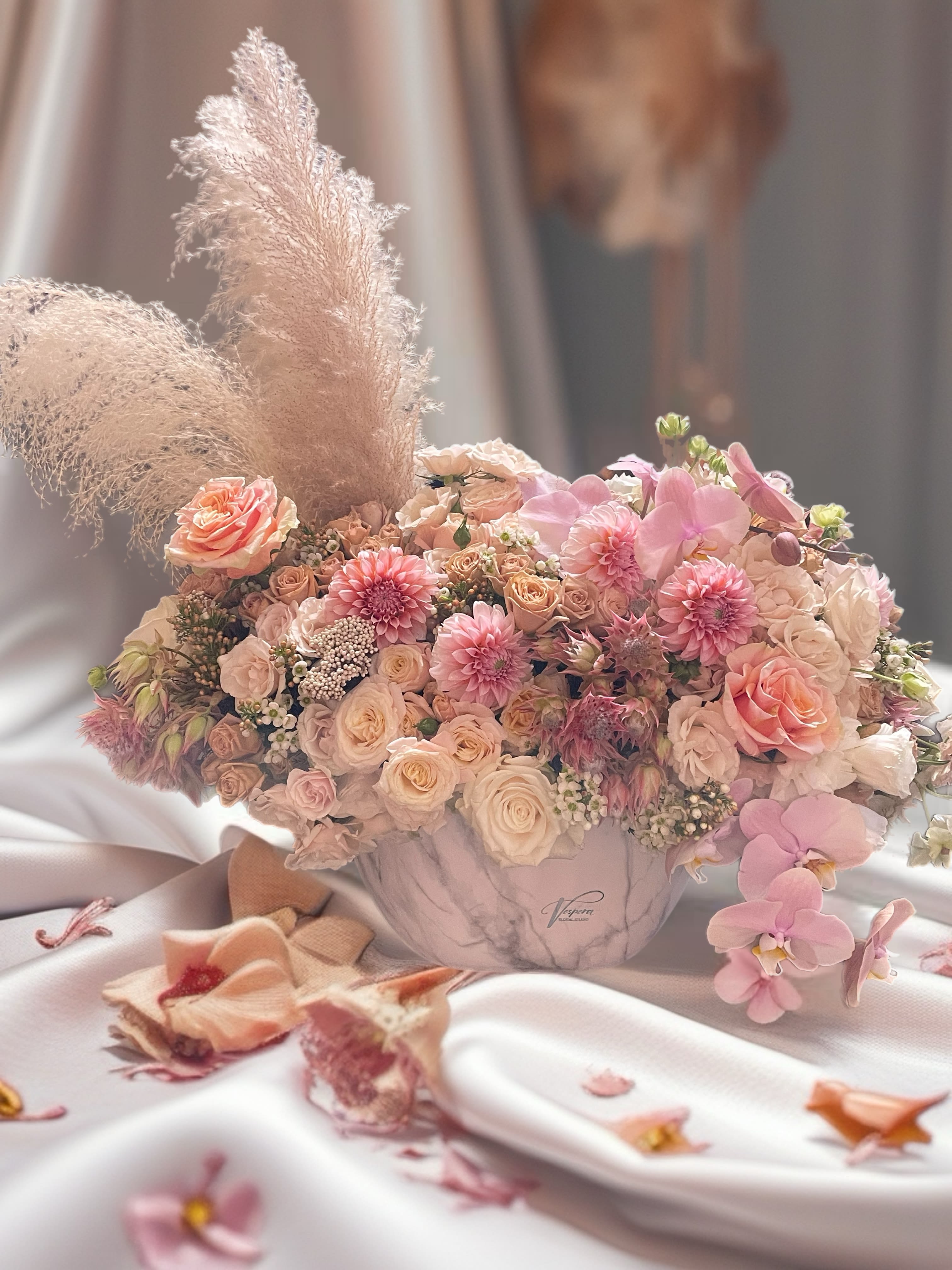 Blush and peach bouquet in a marble vase with orchids and pampas grass