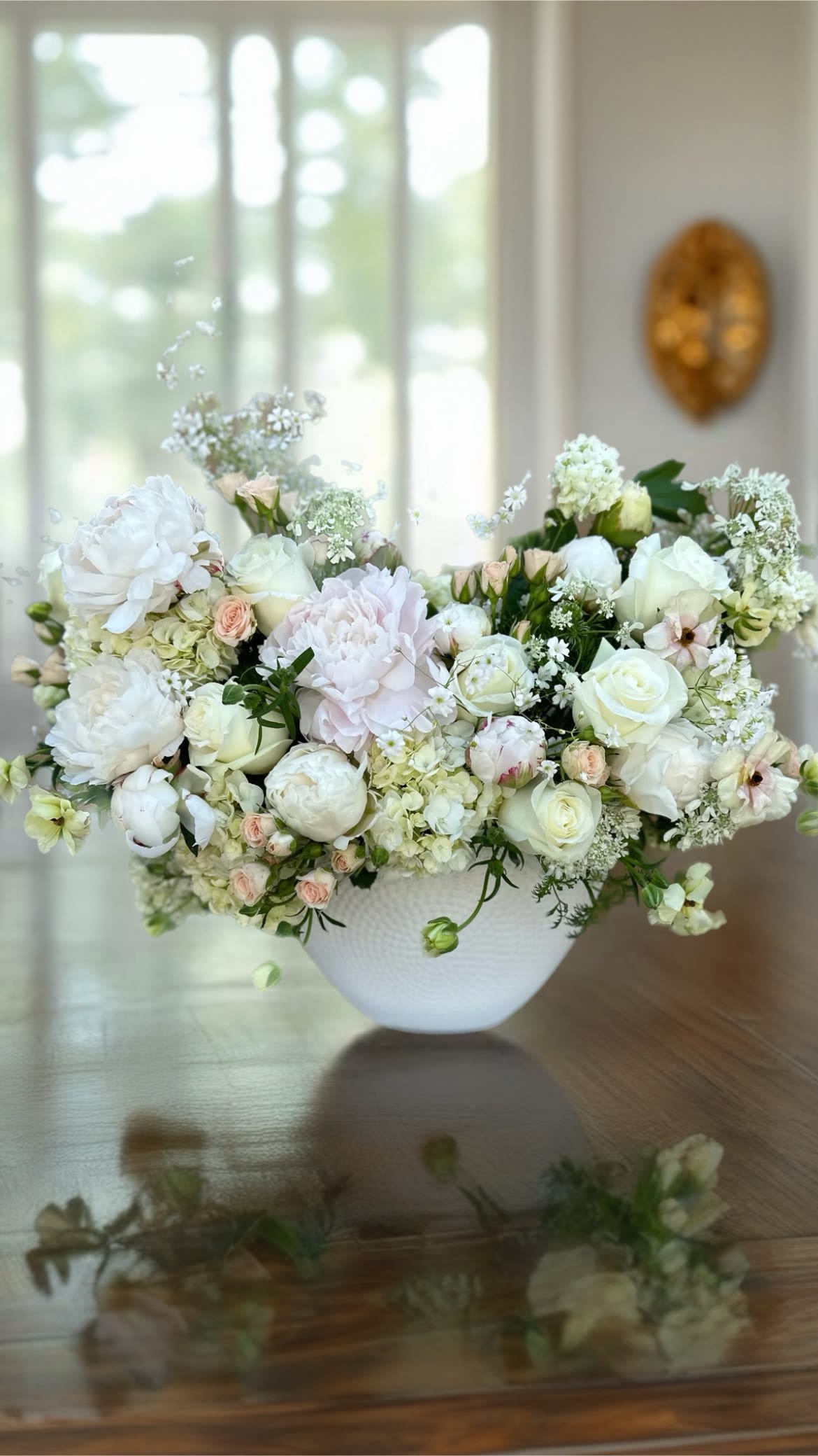 White and blush floral arrangement in a white bowl vase