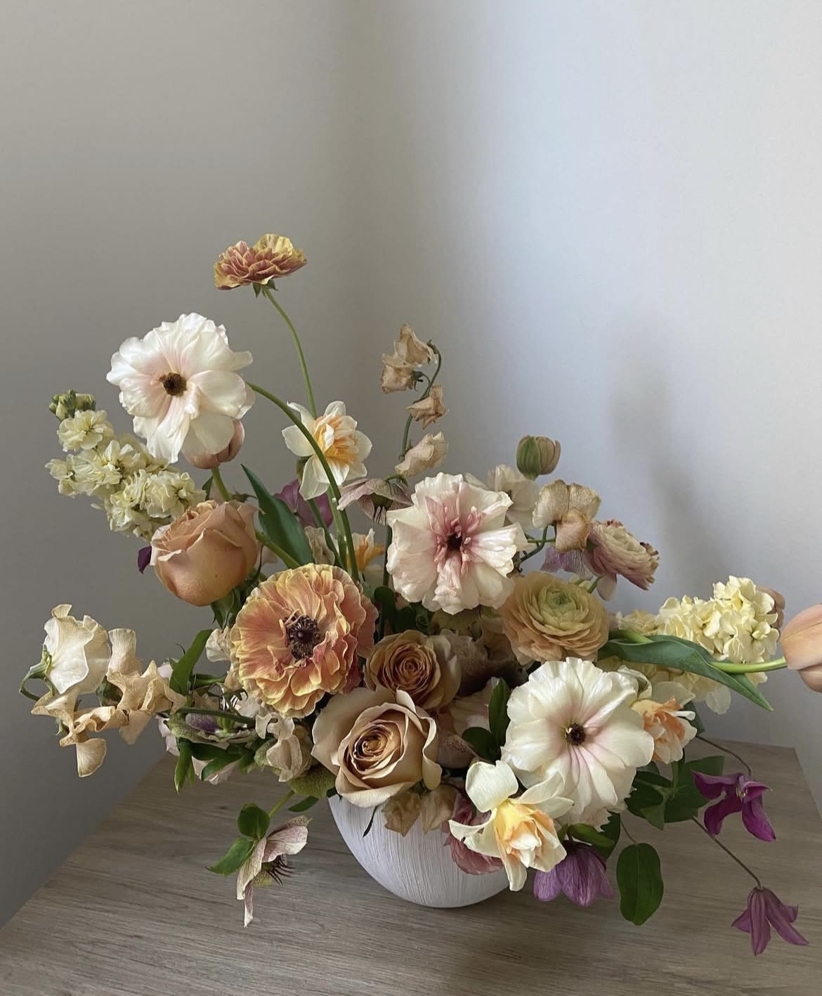 Mixed pastel flower arrangement in a white vase on a table