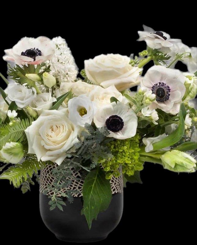 White roses and anemones arranged in a dark vase