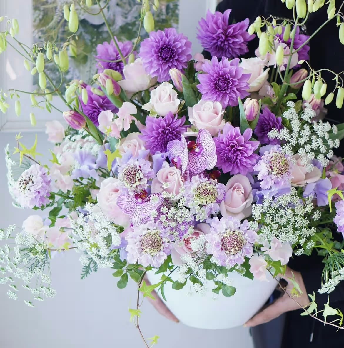 Large bouquet of purple and pale pink flowers in a white vase