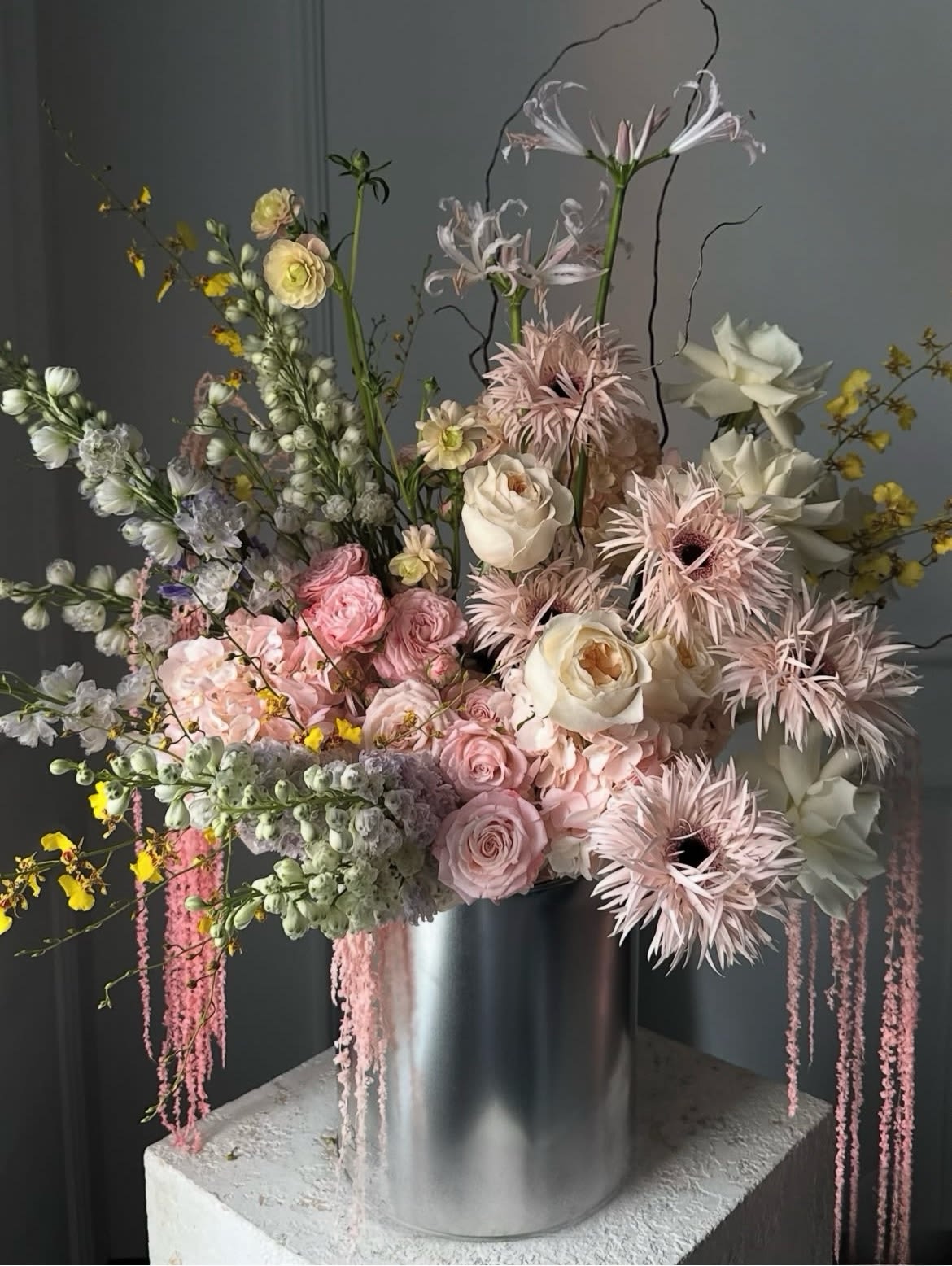 Tall pastel floral arrangement in a silver cylinder vase