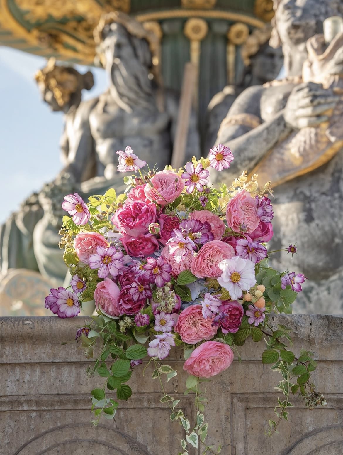 Pink bouquet of roses and daisy-like flowers on a stone ledge