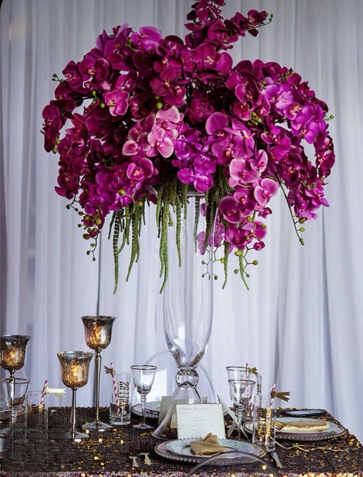 Tall arrangement of purple orchids in a clear glass vase