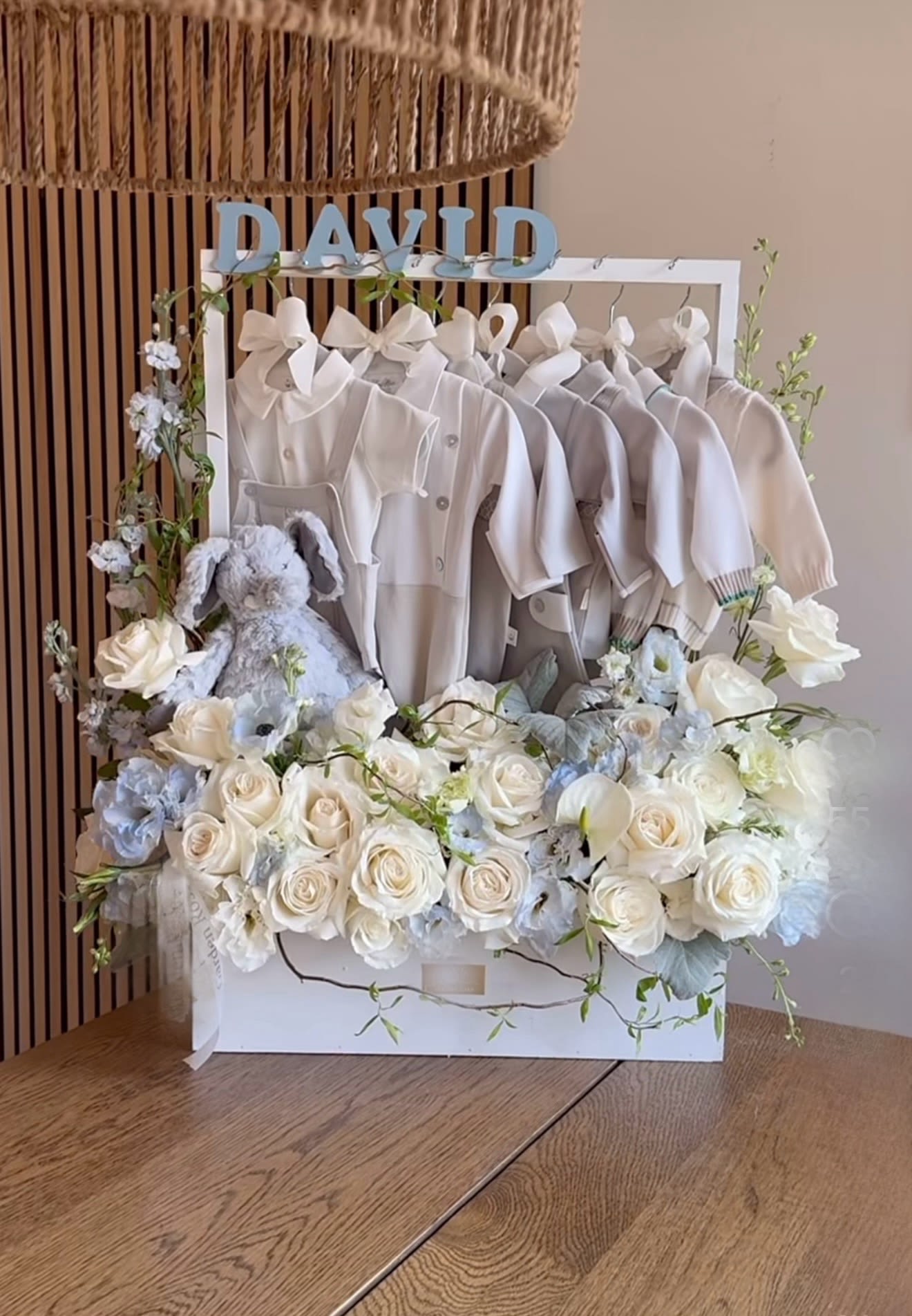 White floral gift box with baby clothes, a plush bunny, and the name David