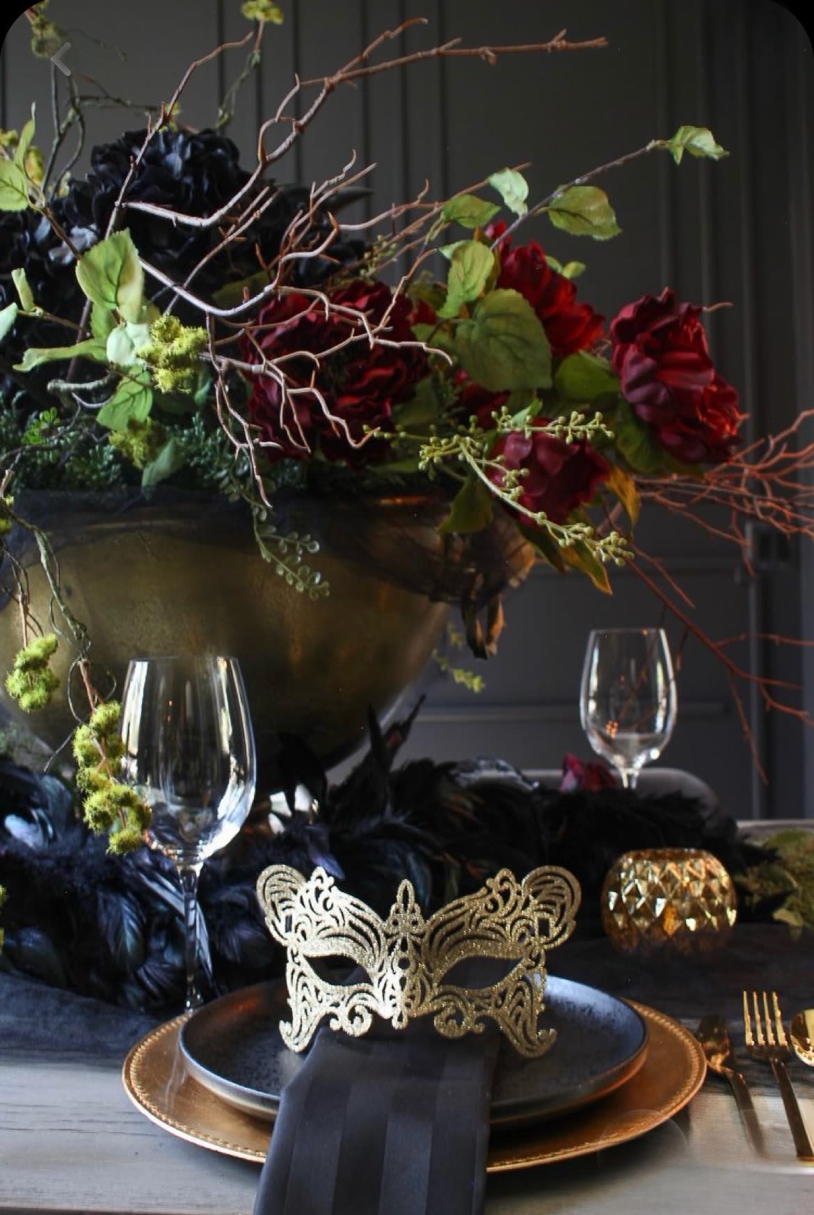 Dark floral centerpiece with red blooms in a gold bowl on a decorated table