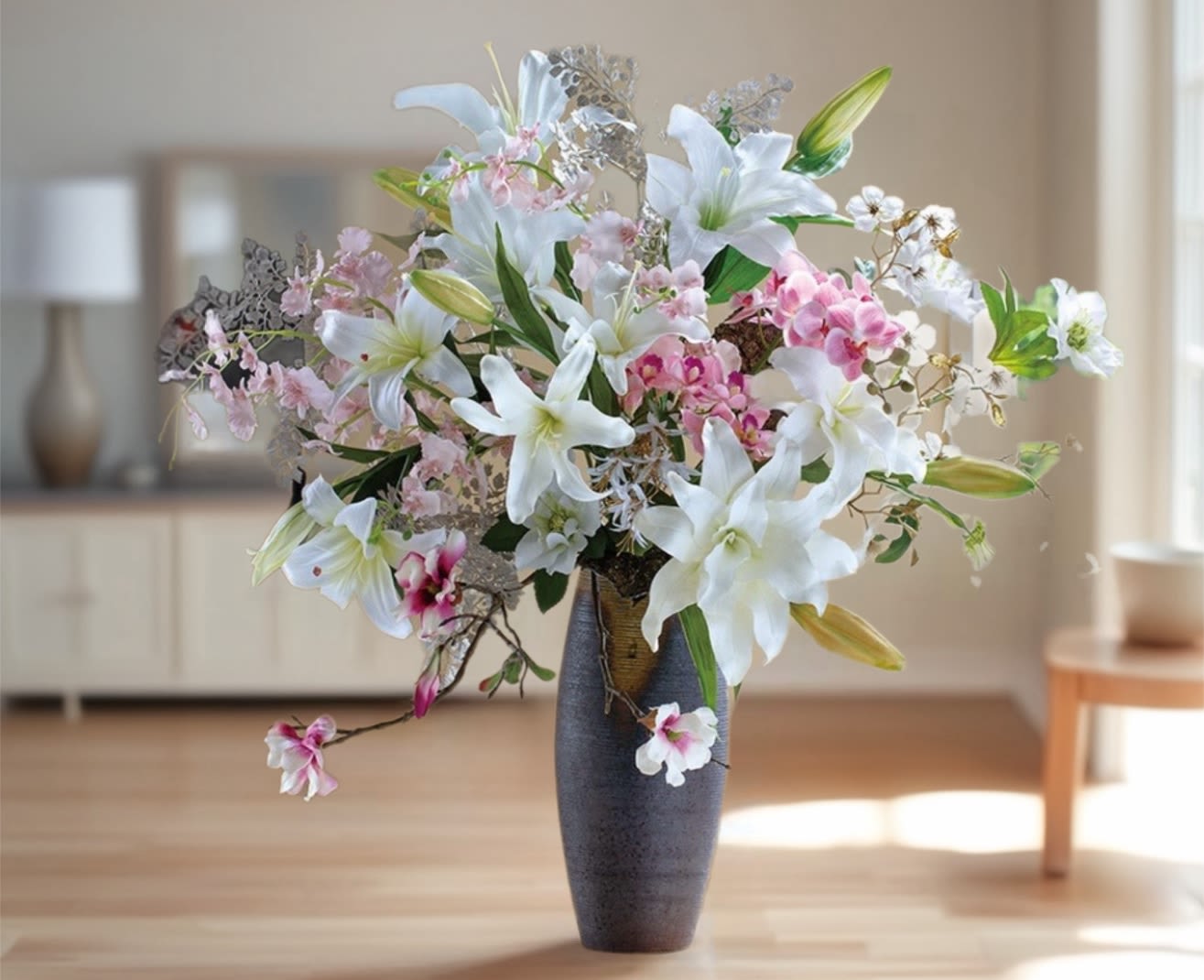 White lilies and pink orchids in a tall dark vase