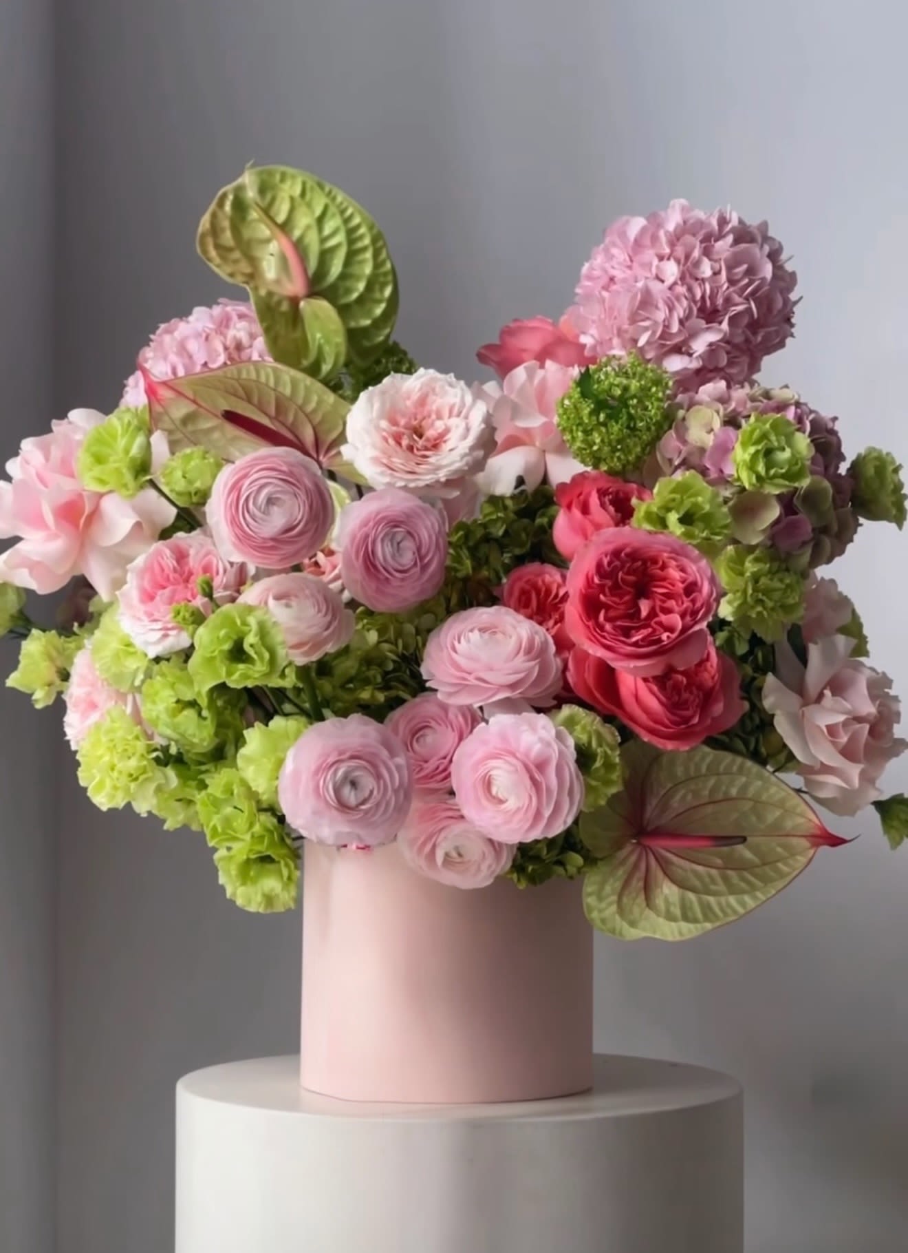 Pink and green floral arrangement in a blush vase