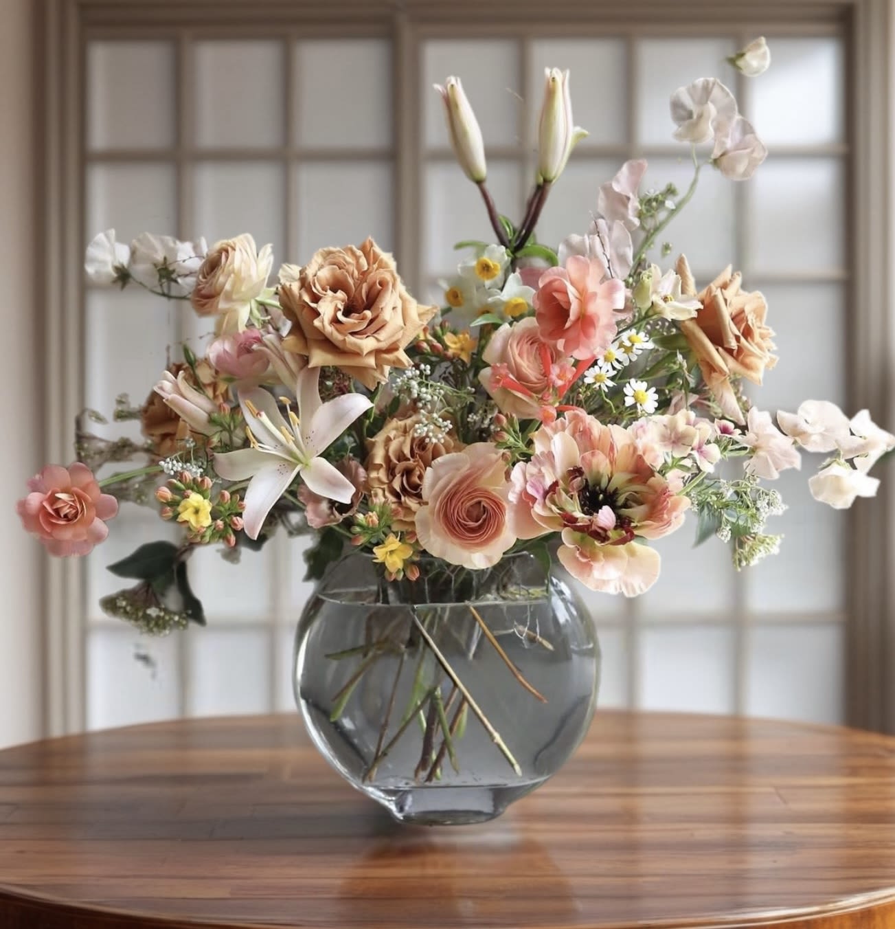 Peach and white mixed flower arrangement in a glass vase