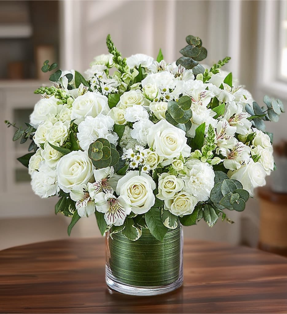 White rose bouquet in a glass vase with green foliage