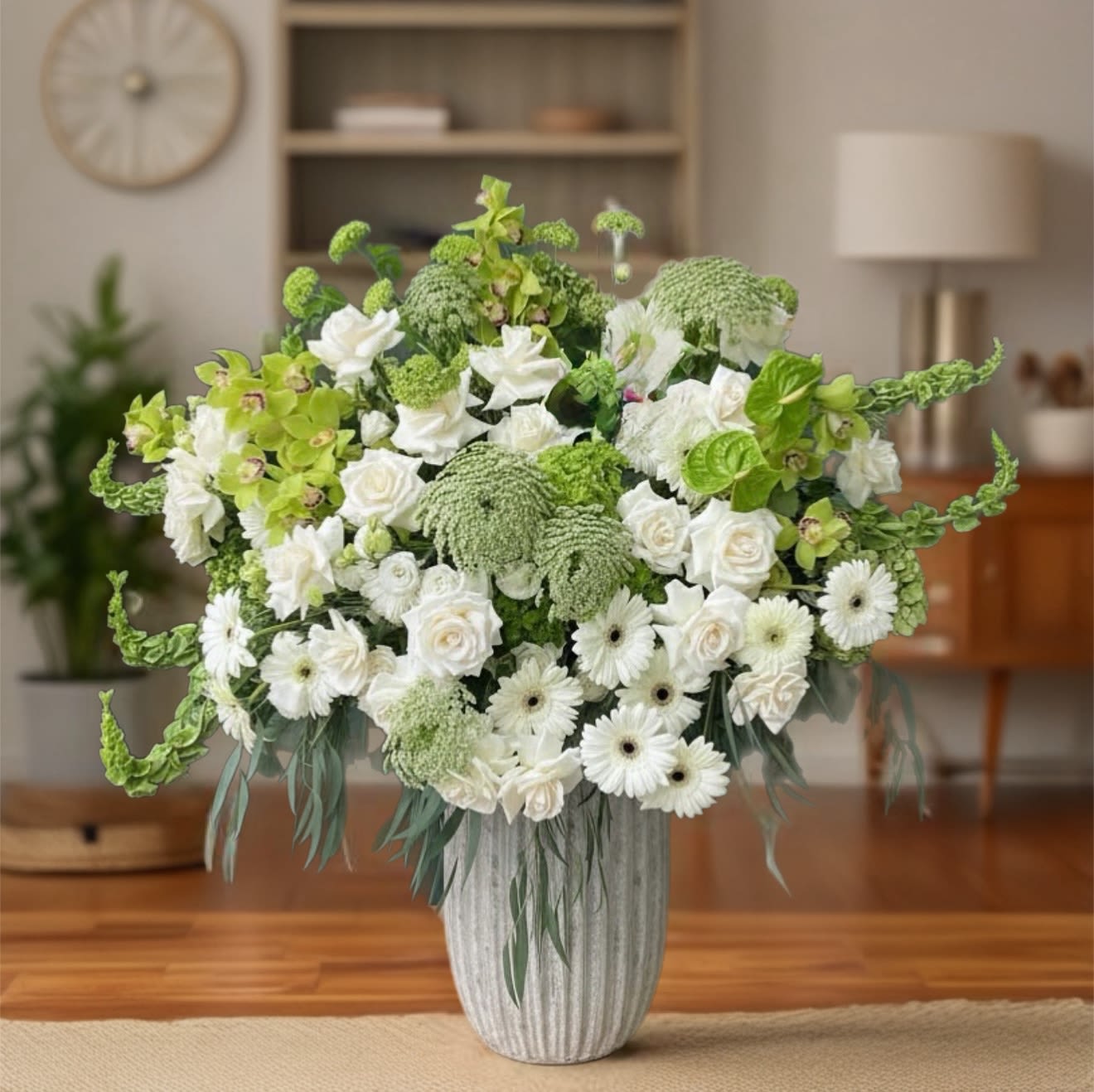 White and green floral arrangement in a ribbed vase