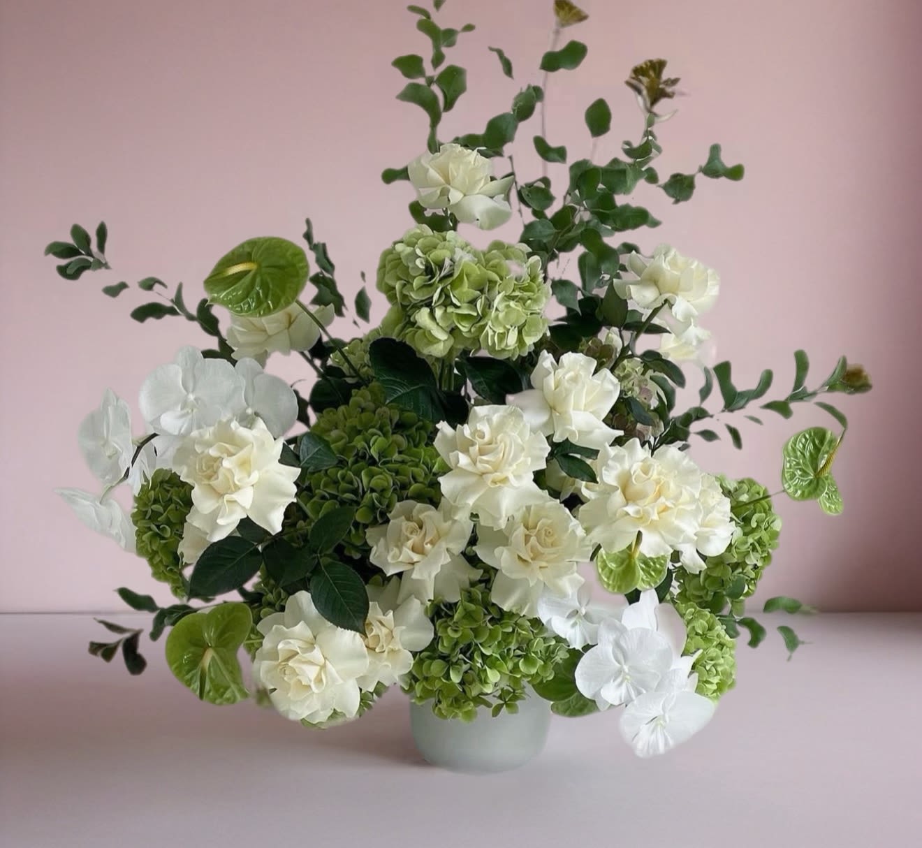 White and green floral arrangement in a pale vase