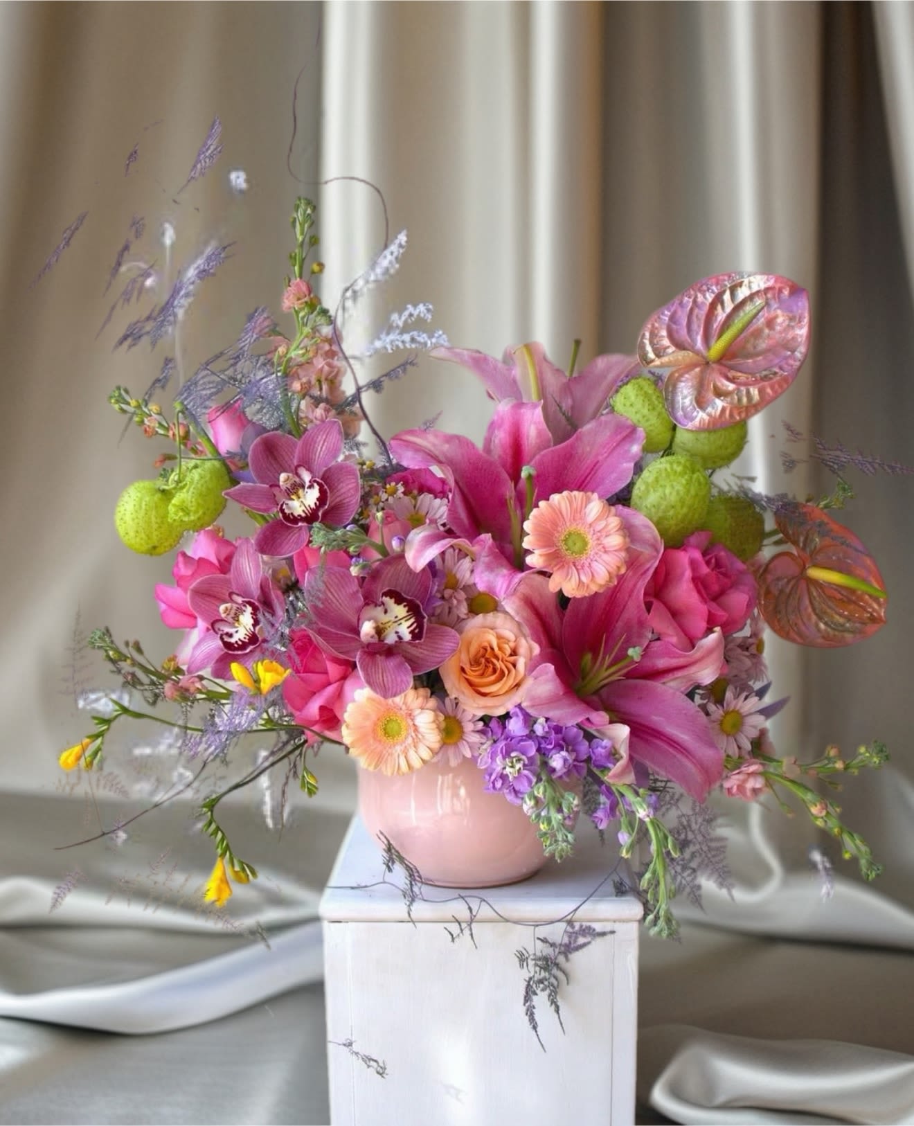 Pink and purple floral arrangement in a pale pink vase