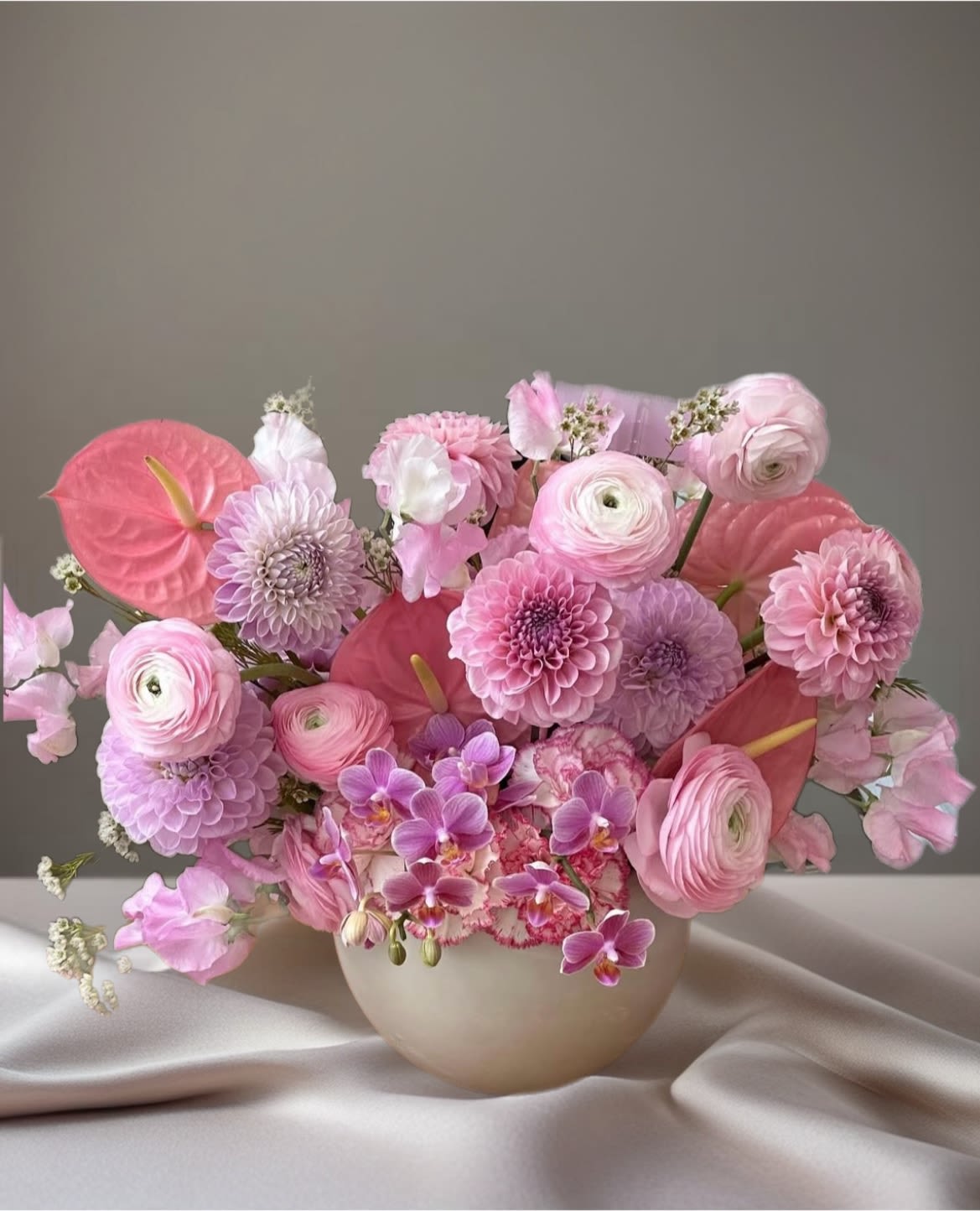 Allison , Day 2  - Soft blush and garden-bright color make this event bouquet a graceful choice for weddings, showers, and springtime celebrations. These flowers for events blend calla lilies, ranunculus, anemones, roses, dahlias and orchids into rounded, hand-held-style compositions that read delicate and elegant-perfect when you want the person you're celebrating to feel seen and beautifully honored.  Each arrangement is layered with textures: pale pink and green-pink anthurium or calla focal blooms, clusters of light green hydrangea, tightly gathered ranunculus and roses in pinks, lavenders, corals and yellows, plus airy filler for a soft, garden-style silhouette. Options are presented in a clear glass vase wrapped with burlap and tied in twine for a rustic touch, or in a low ceramic vase for a more polished table centerpiece; sizes are compact and meant to sit comfortably on reception tables or cocktail rounds.  Choose this design to mark a bridal shower, anniversary, birthday, or any event where a romantic, uplifted mood is the aim-the mix of pastel and vivid blooms creates both warmth and celebration. Care is simple: keep water fresh, trim stems every few days, and place away from direct heat to extend the life of the blooms.