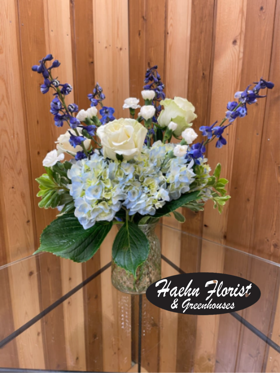 White roses and blue hydrangeas in a glass vase