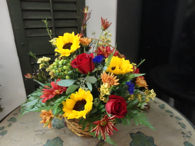 Basket arrangement with sunflowers, red roses, and mixed flowers