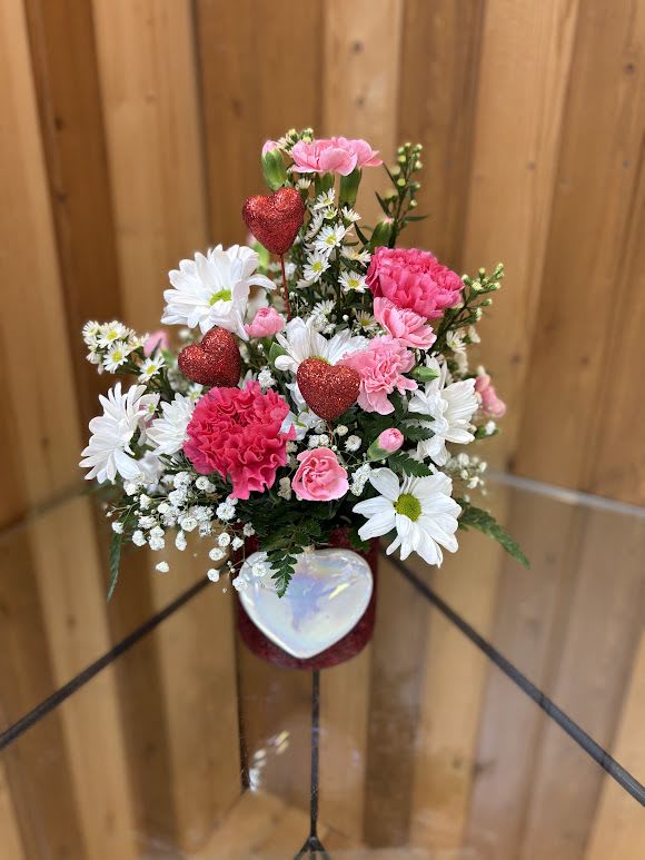 Pink and white flower arrangement with glittery red hearts in a vase