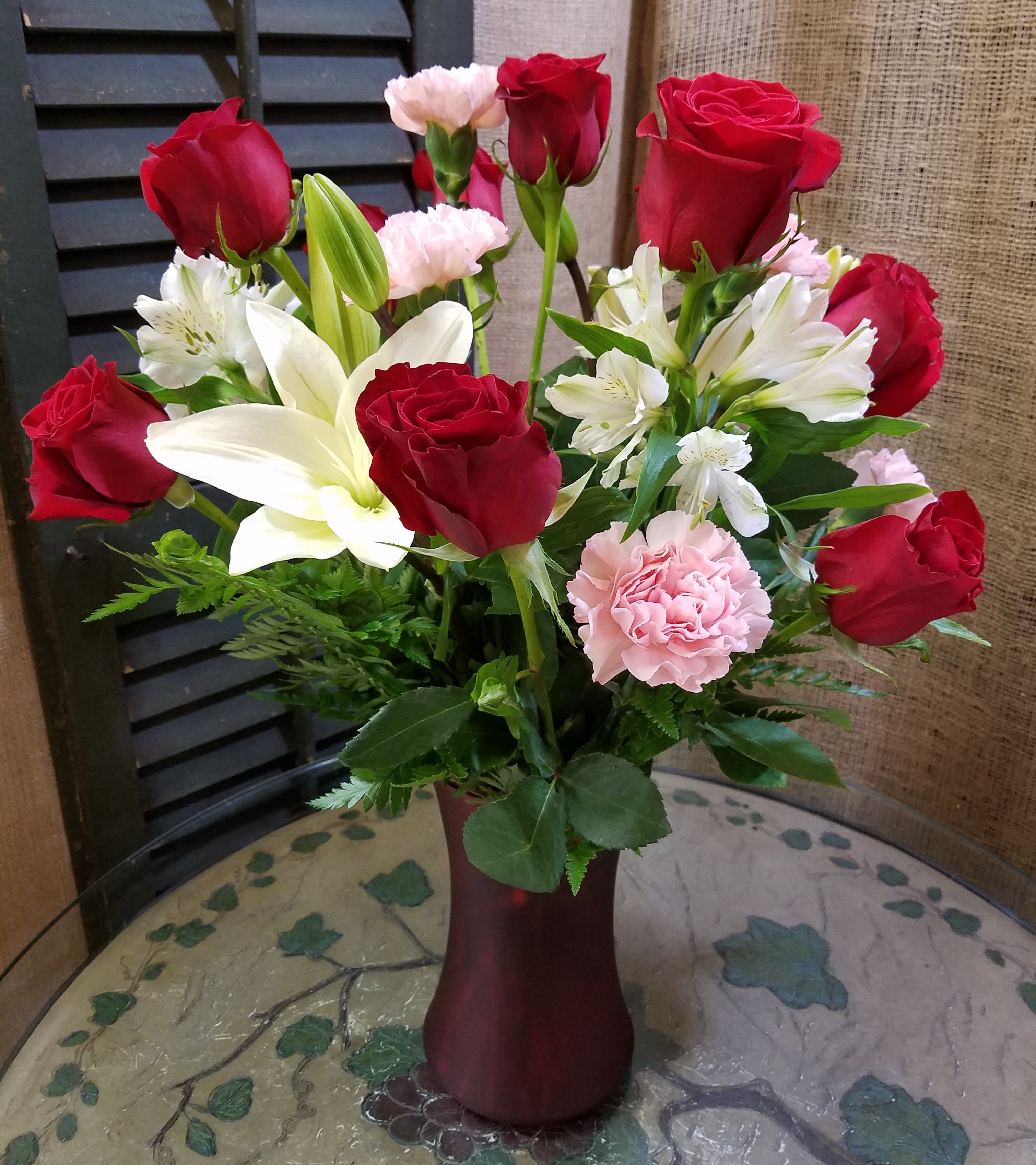 Bouquet of red roses, white lilies, and pink carnations in a vase
