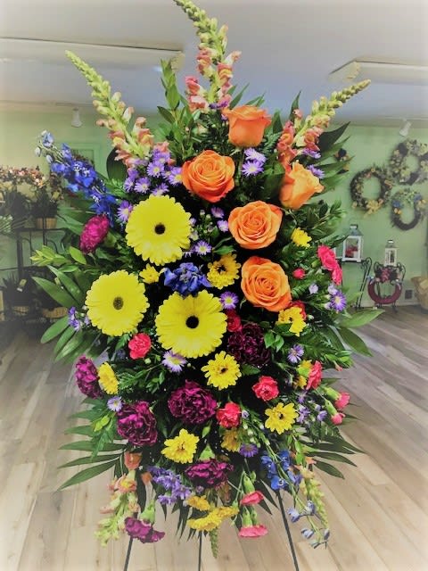 Celebration of Life Spray (COL) - One standing spray arrives with snap dragons, roses, yellow gerberas, hot pink mini carnations, and foliage accents on an easel. Approximately 18" W x 46" H. TF203-8 
