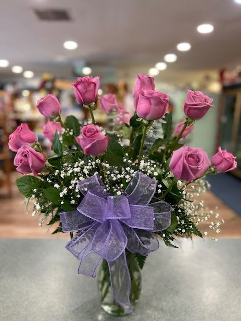 Pink roses in a glass vase with a purple bow