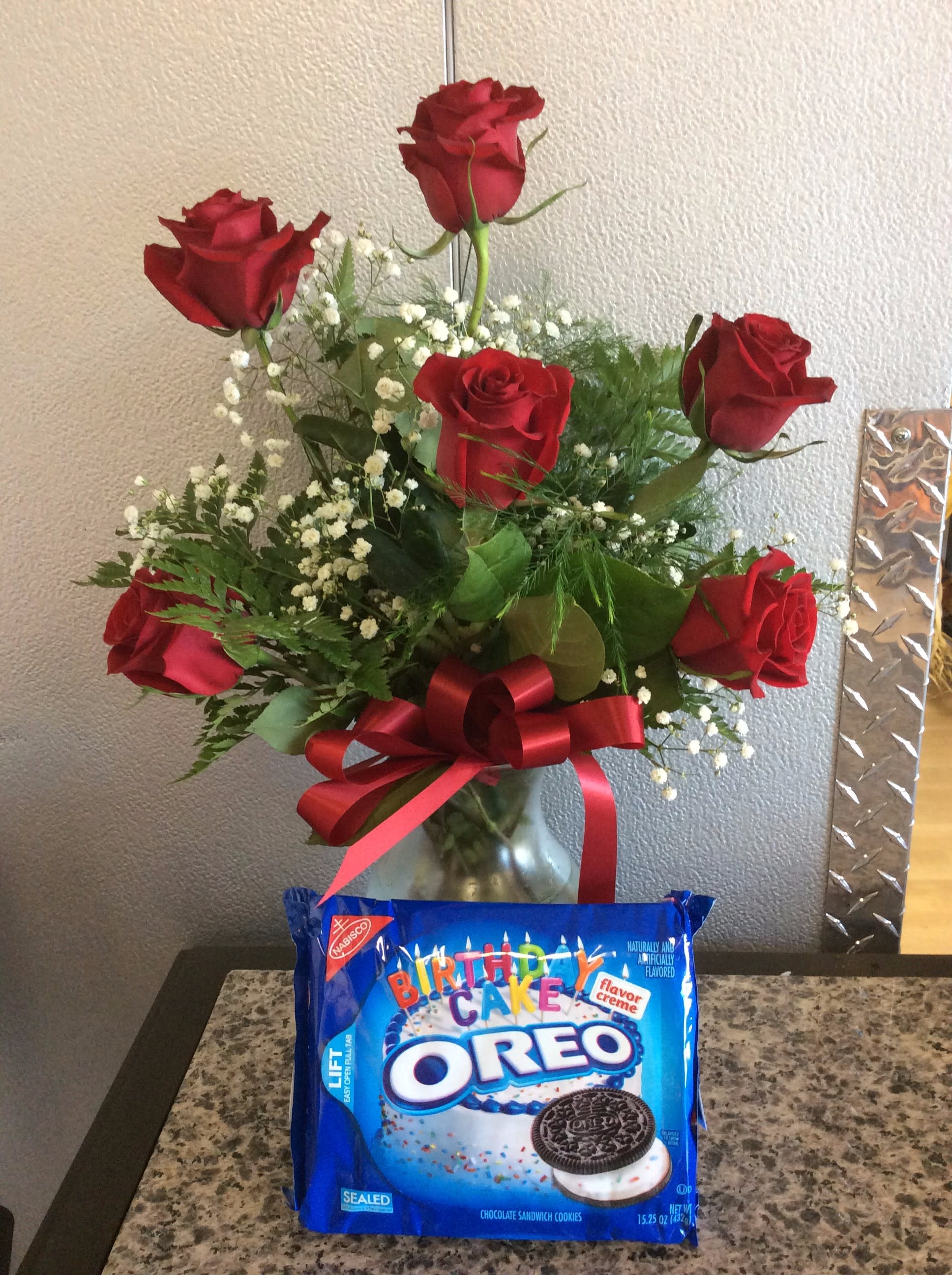 Red roses in a glass vase with a red ribbon and a birthday Oreo cookie package