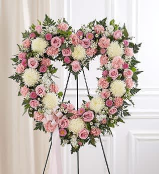 Heart-shaped pink and white floral wreath on a stand