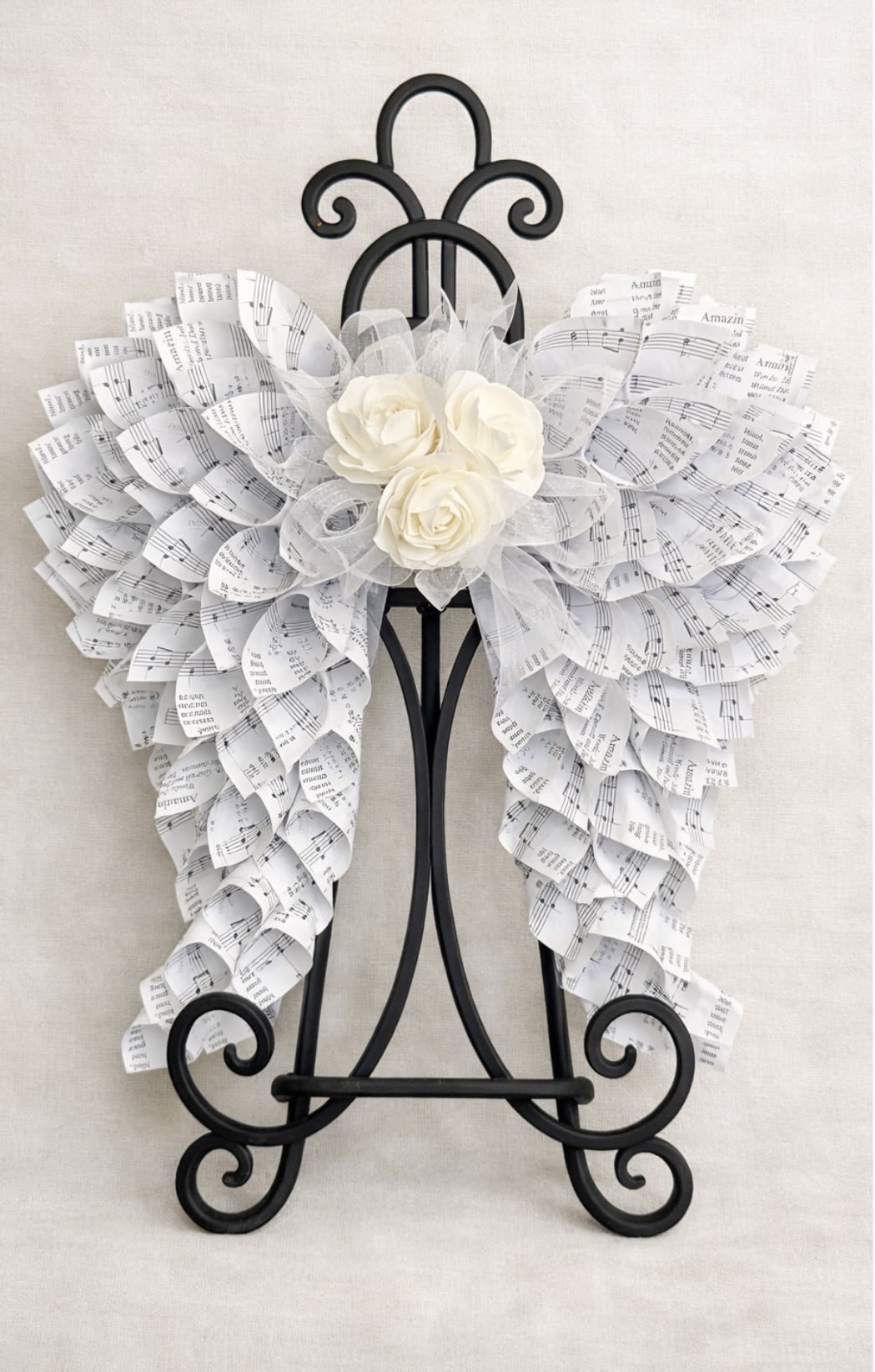 Angel Wings 12"x12" Floral Center - 12"×12" angel wings made of hymnal pages with floral and ribbon center. The perfect gift to honor someone.  Can be hung on the wall or displayed on an easel in the home of a loved one. (Easel not included in price) 