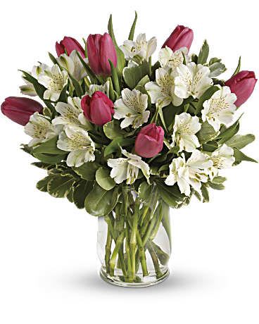Pink tulips and white alstroemeria arranged in a clear glass vase