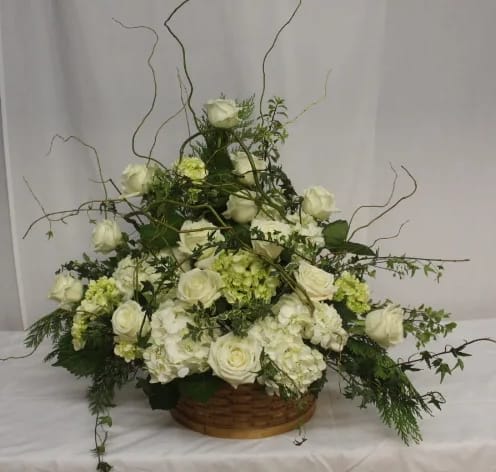 White rose and hydrangea arrangement in a low basket with curly branches
