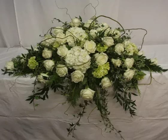 White rose and hydrangea floral arrangement with trailing greenery