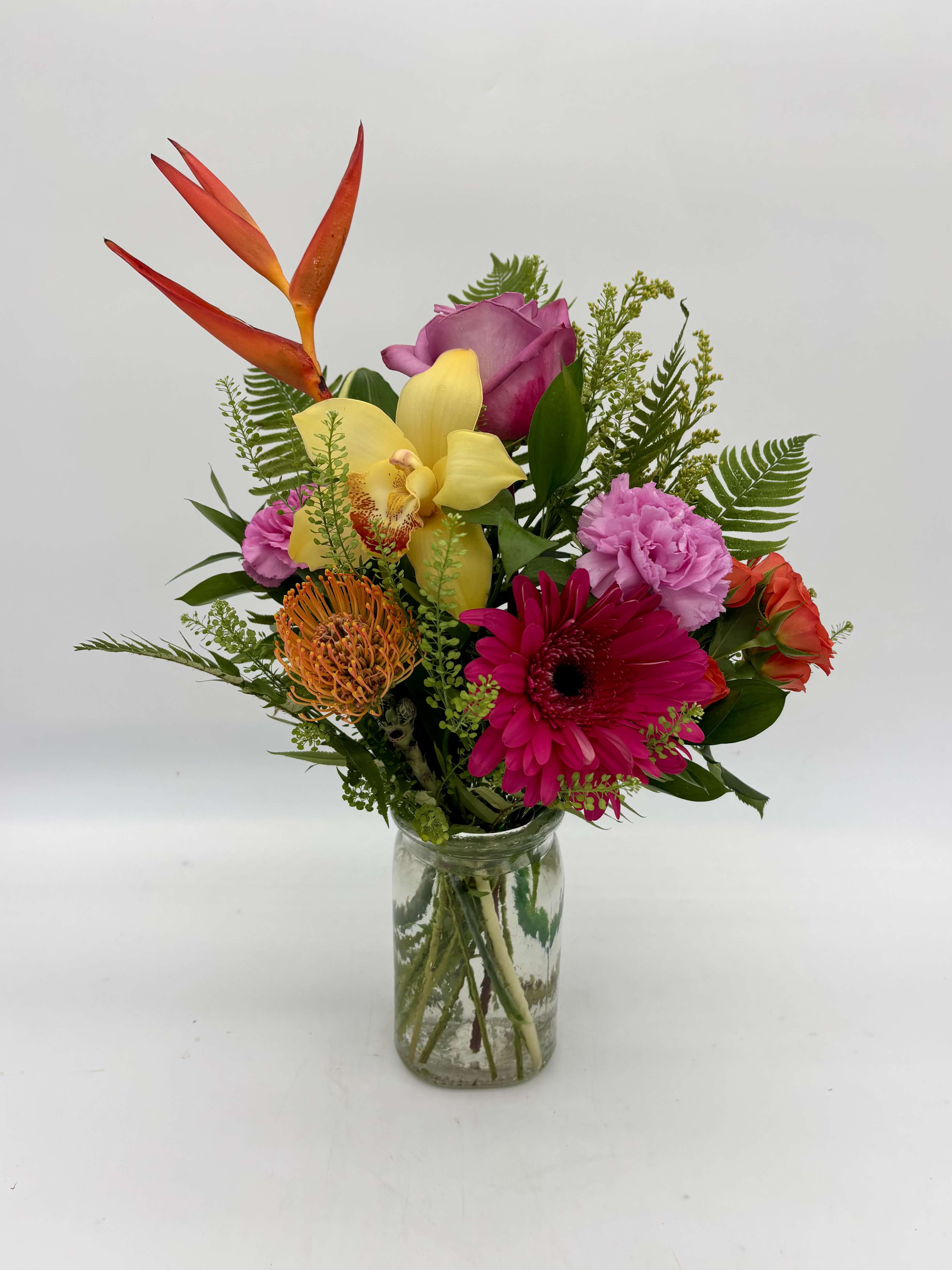 Island Tropic - Island Tropic captures the spirit of a sun-soaked island escape with a vibrant blend of yellow, hot pink, purple, and orange blooms. Featuring exotic yellow cymbidium orchids, striking heliconia, and bold pincushion protea, this tropical arrangement evokes warm ocean breezes, and the colorful beauty of paradise.