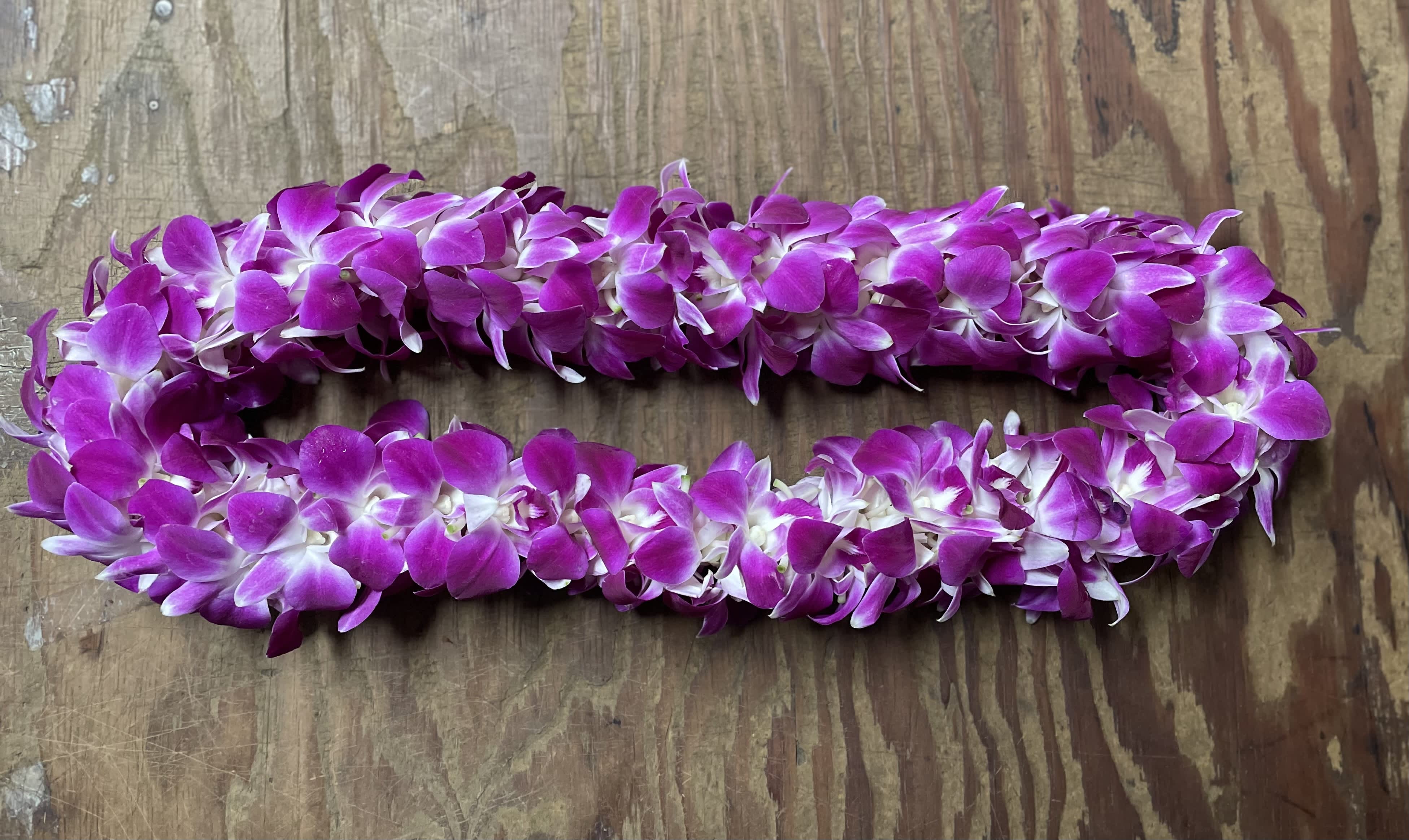 Two purple orchid leis on a wooden surface