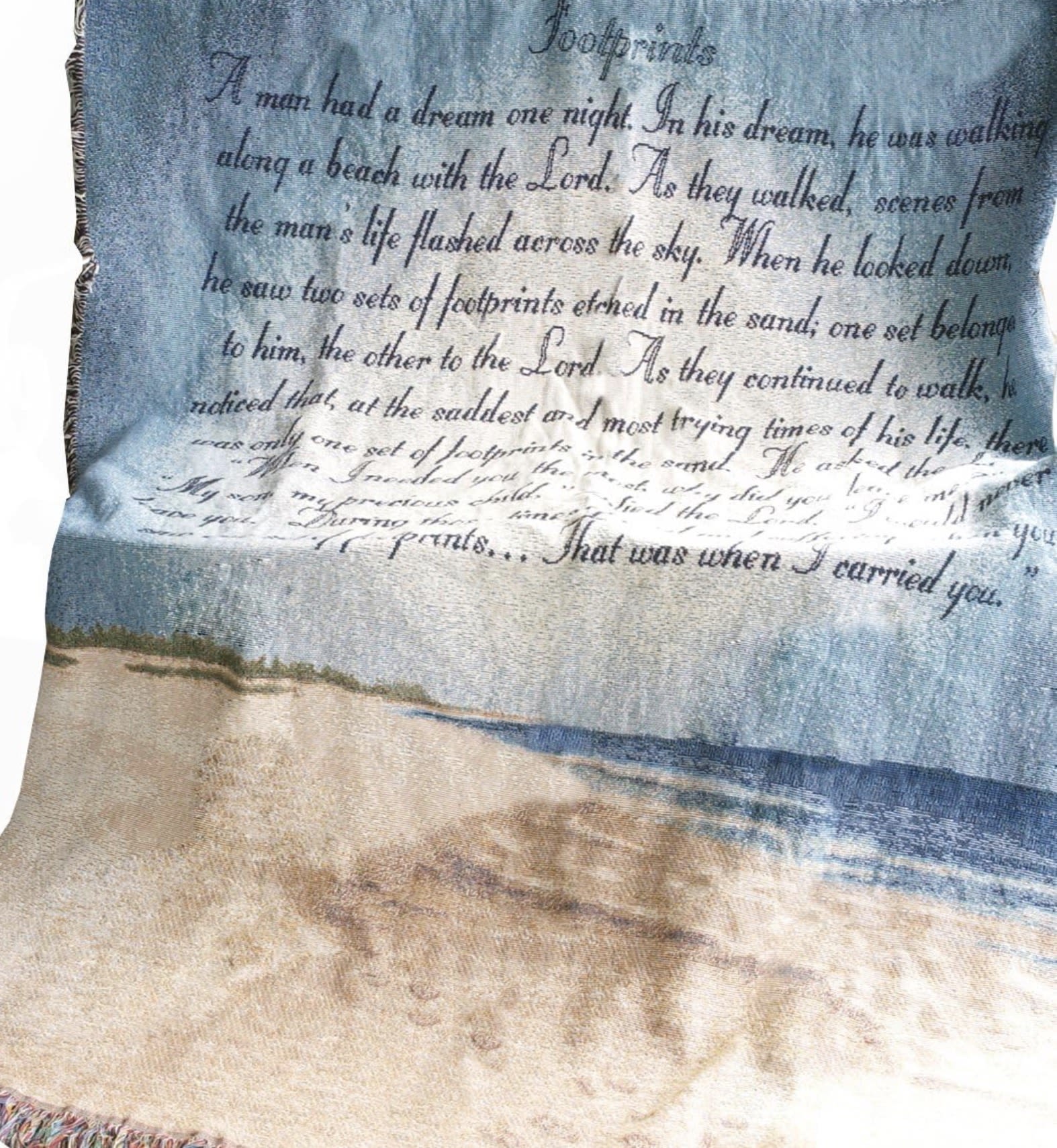 Footprints Throw - The Footprints Inspirational Tapestry Throw is a beautiful keepsake designed to inspire faith, peace, encouragement, and comfort through every season of life. Featuring the beloved “Footprints” poem with calming coastal artwork, this woven tapestry creates a meaningful display for birthdays, encouragement gifts, church gatherings, recovery, celebrations of faith, home décor, and life’s most heartfelt moments.  Available as a neatly folded keepsake tied with a sheer bow, displayed on a temporary easel for events or gatherings, or enhanced with a coordinating fresh floral spray across the top, each presentation style offers warmth, elegance, and lasting beauty. The floral accents are custom designed to complement the tapestry while creating a soft, realistic display suitable for churches, foyers, visitation settings, celebrations, or meaningful occasions.  Unlike temporary gifts, this tapestry throw becomes a treasured keepsake families and recipients can display, use, and cherish for years to come. The peaceful beach imagery and timeless message create an emotional connection that feels personal, uplifting, and comforting without being overly formal.  Designed to offer both visual beauty and heartfelt meaning, the Footprints Tapestry Throw is a timeless gift that blends inspiration, faith, and elegant presentation into one unforgettable piece.