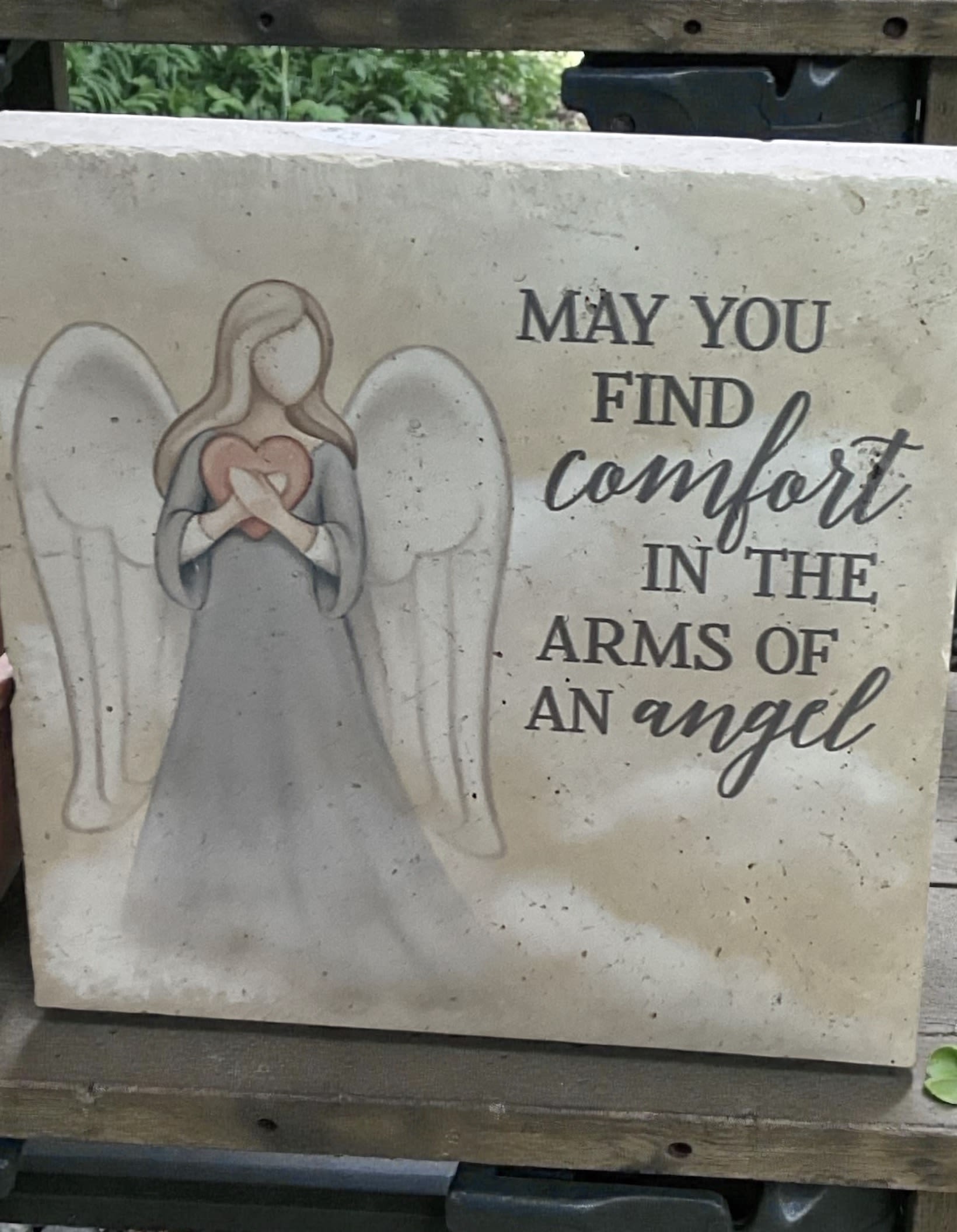 Arms of an Angel Stone - The Arms of an Angel Plaque is a beautiful expression of faith, encouragement, comfort, and hope. Featuring a graceful angel design and the heartfelt sentiment, “May You Find Comfort in the Arms of an Angel,” this substantial stone plaque serves as a meaningful reminder that support, strength, and peace can often be found during life’s most challenging moments.  Its timeless design makes it a thoughtful gift for friends, family members, church members, caregivers, teachers, neighbors, or anyone facing a difficult season. Whether someone is recovering from an illness, navigating a personal challenge, celebrating a milestone in faith, or simply in need of encouragement, this plaque offers a lasting message of comfort and reassurance.  The natural stone appearance and classic styling complement a variety of decorating styles, making it suitable for display on a bookshelf, mantel, desk, entry table, covered porch, or special display space. Each plaque is accented with a coordinating ribbon and arrives ready to display.  The Arms of an Angel Plaque is also an appropriate keepsake for remembrance, sympathy, memorial occasions, and honoring cherished memories. Its uplifting message and enduring design create a meaningful gift that can be appreciated long after it is received.  A thoughtful gift for encouragement, faith-based occasions, thinking of you moments, support during difficult times, sympathy, remembrance, and everyday inspiration.