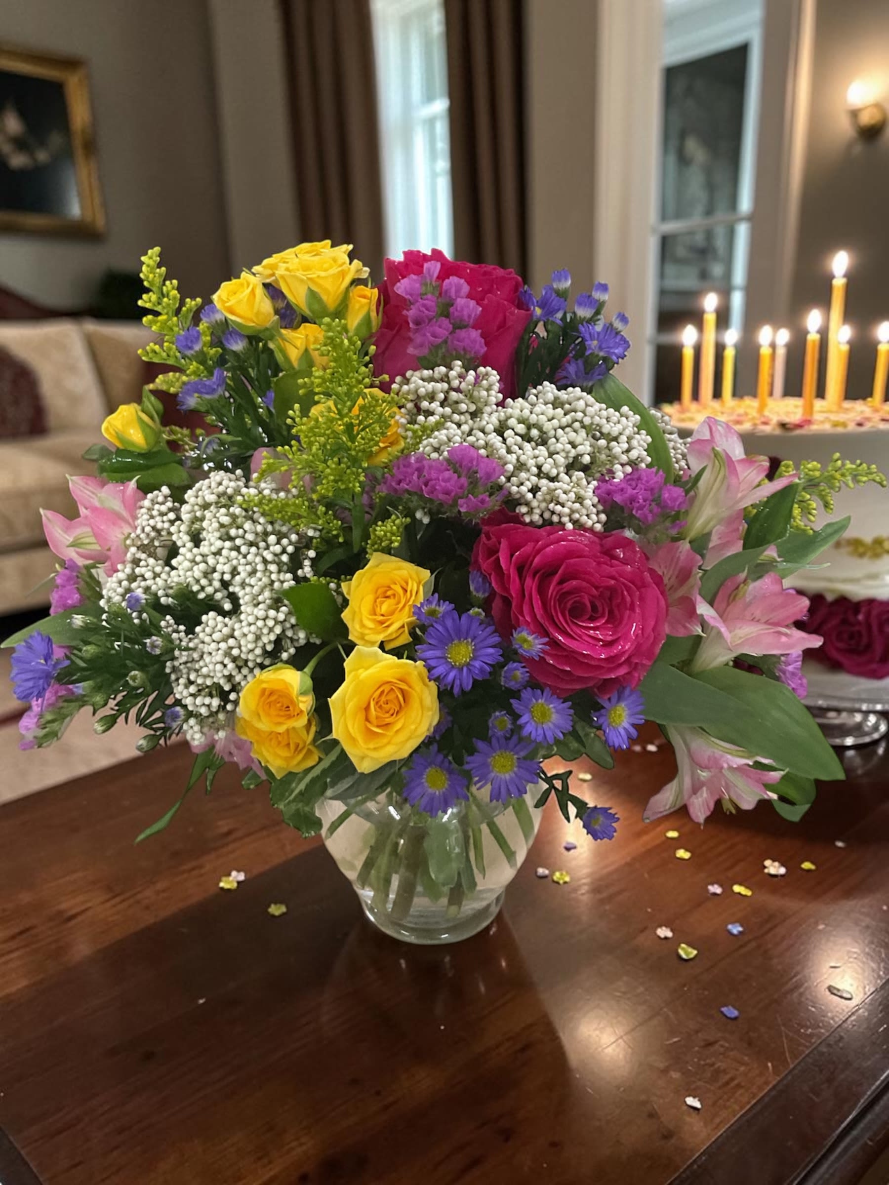Confetti Wishes - Confetti Wishes is a bright, joyful arrangement designed to celebrate life’s happiest moments. Featuring a vibrant mix of spray roses, premium roses, alstroemeria lilies, statice, solidago, rice flower, and seasonal accents, this design is full of color, texture, and energy.  Arranged in a clear glass vase, Confetti Wishes brings together bold and soft tones in a balanced, eye-catching style that feels festive without being overwhelming. The combination of lush blooms and airy fillers creates movement and dimension, making it a standout piece for any setting.  Perfect for birthdays, celebrations, congratulations, or simply sending a little extra joy, this arrangement is designed to brighten rooms and lift spirits. Each piece is handcrafted using the freshest available flowers, ensuring a full, fresh look and long-lasting beauty.  Available for local delivery through Aspen Tower Florist, proudly serving Greensburg, Shelbyville, Rushville, Batesville, Westport, Oldenburg, St. Paul, Waldron, and Milroy. Same-day delivery may be available for those last-minute celebrations that still deserve something beautiful.