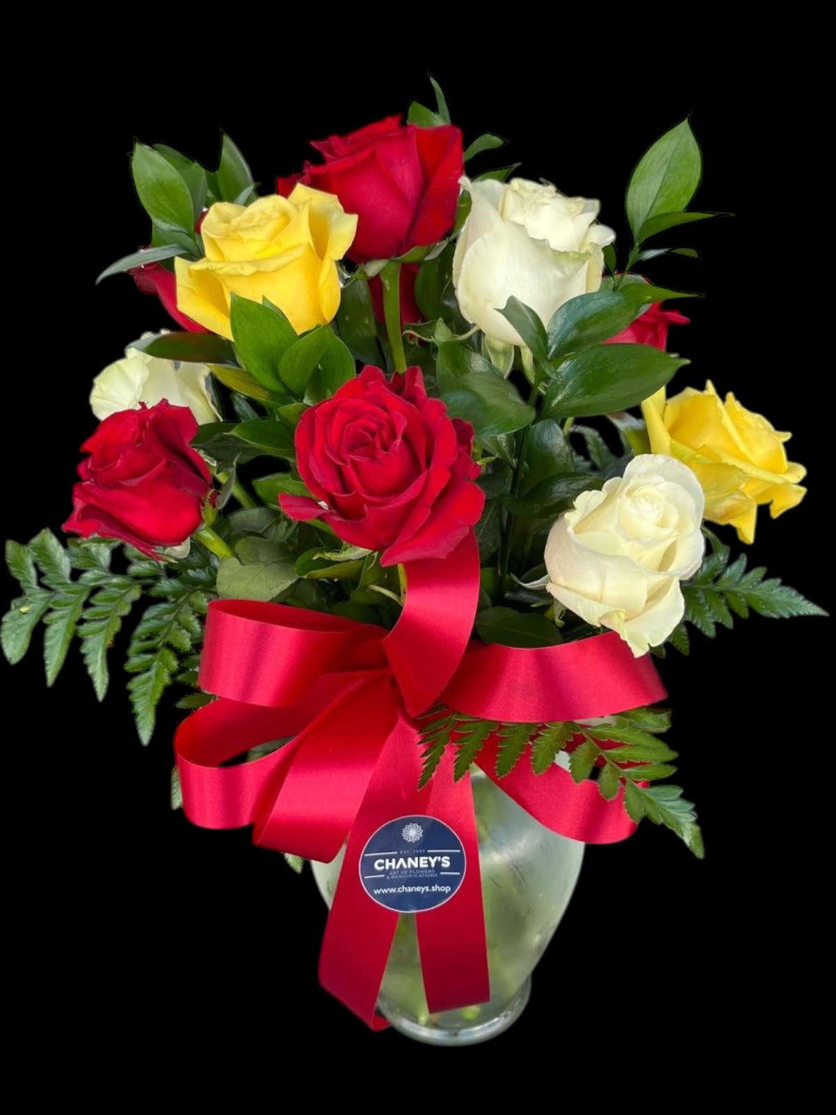 Bouquet of red, yellow, and white roses in a glass vase with a red ribbon