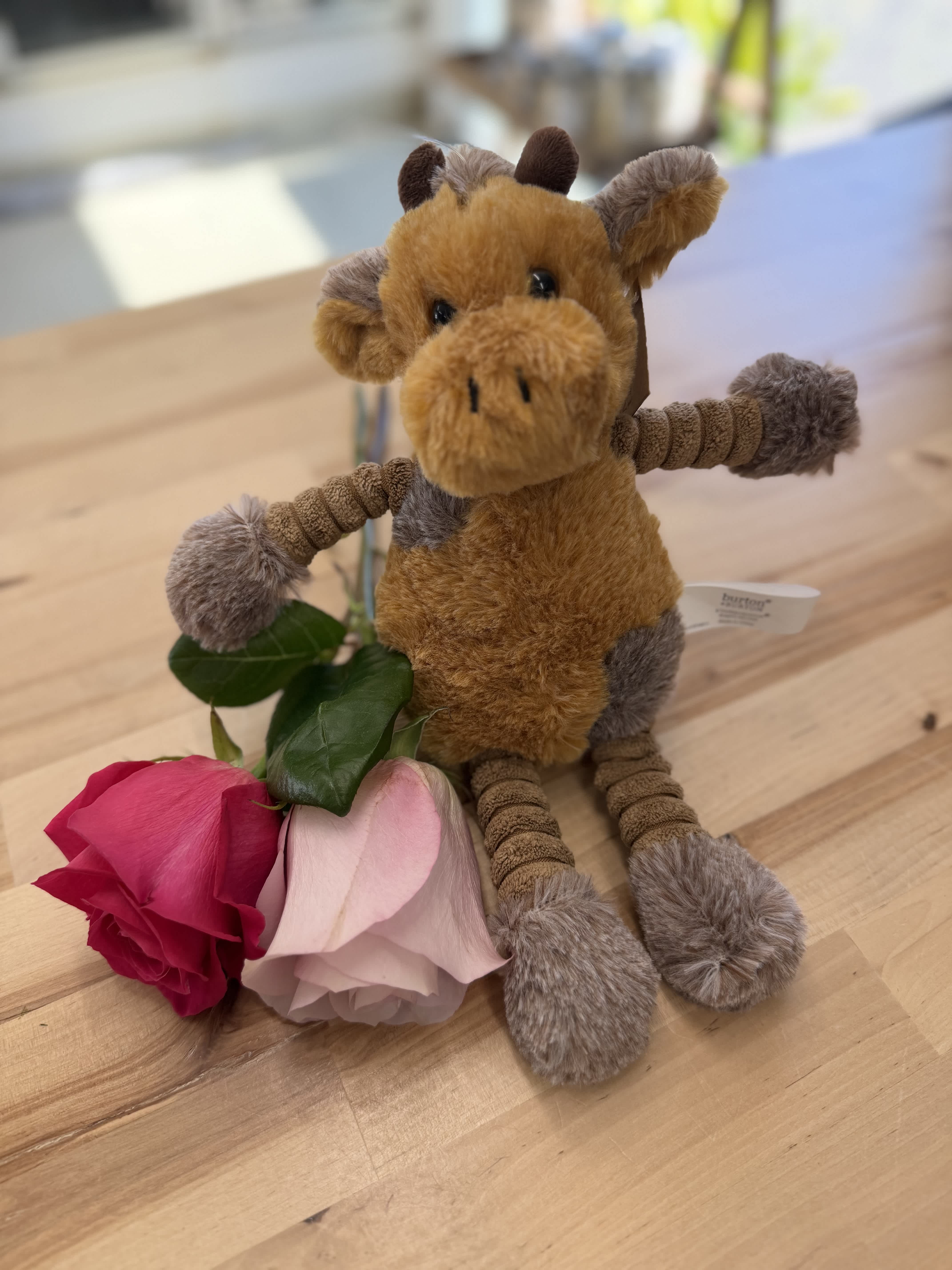 Plush giraffe with two roses on a wooden table