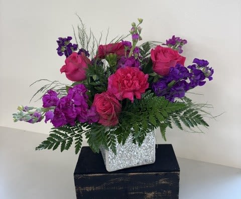 Studio 54 - Turn up the glamour with Studio 54, a bold and vibrant floral arrangement designed to make a statement. Featuring hot pink roses, hot pink carnations, and purple stock, this eye-catching design is arranged in a stunning mirrored cube vase that sparkles like a disco ball. Bursting with color and modern style, it's the perfect gift for birthdays, celebrations, or anyone who loves a little extra shine.