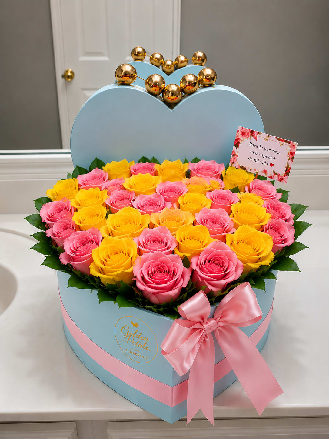 Heart-shaped box of pink and yellow roses with a pink ribbon