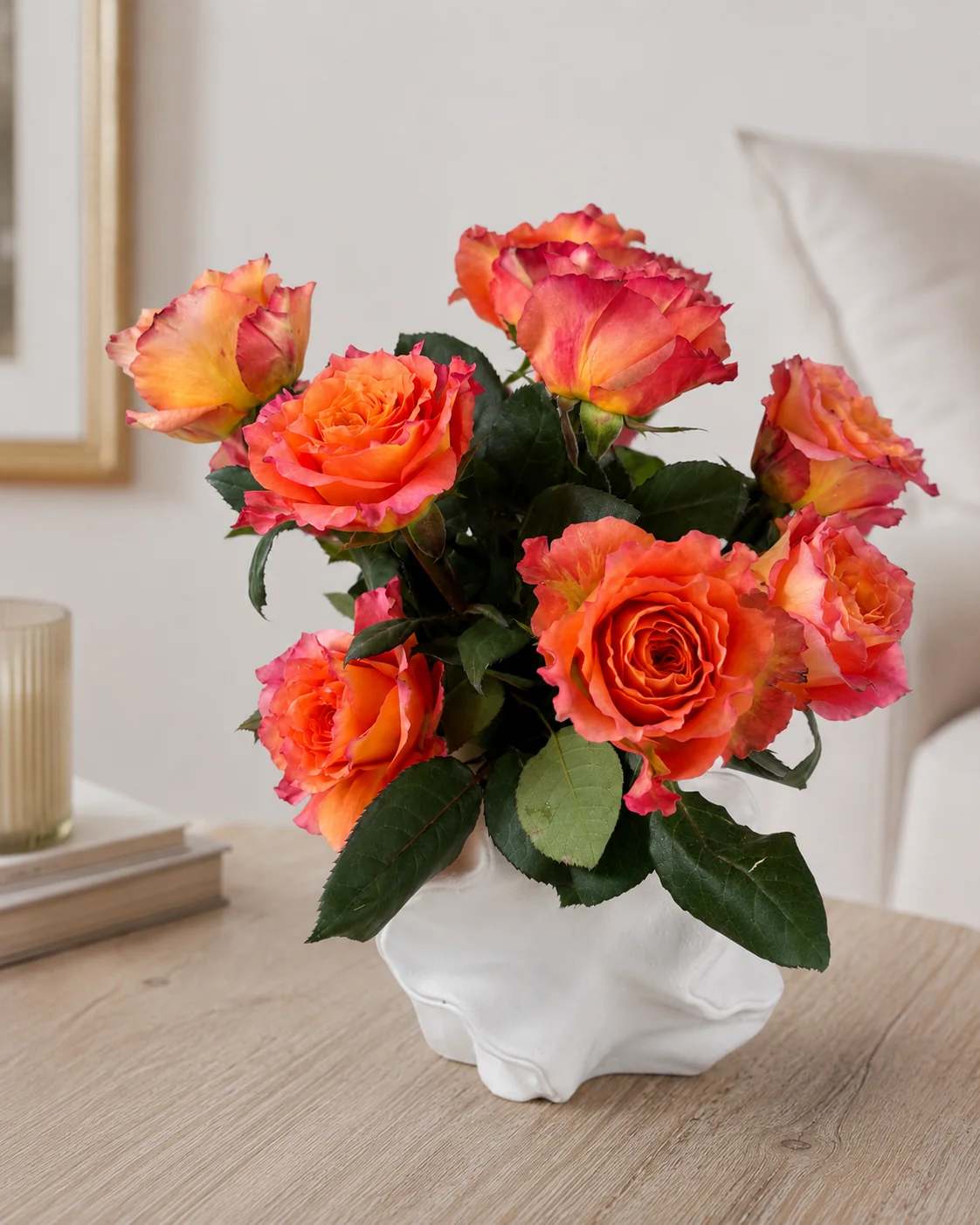 Orange and pink roses in a white ceramic vase