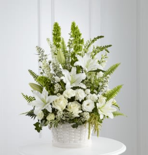 White lilies and roses in a white basket with green accents