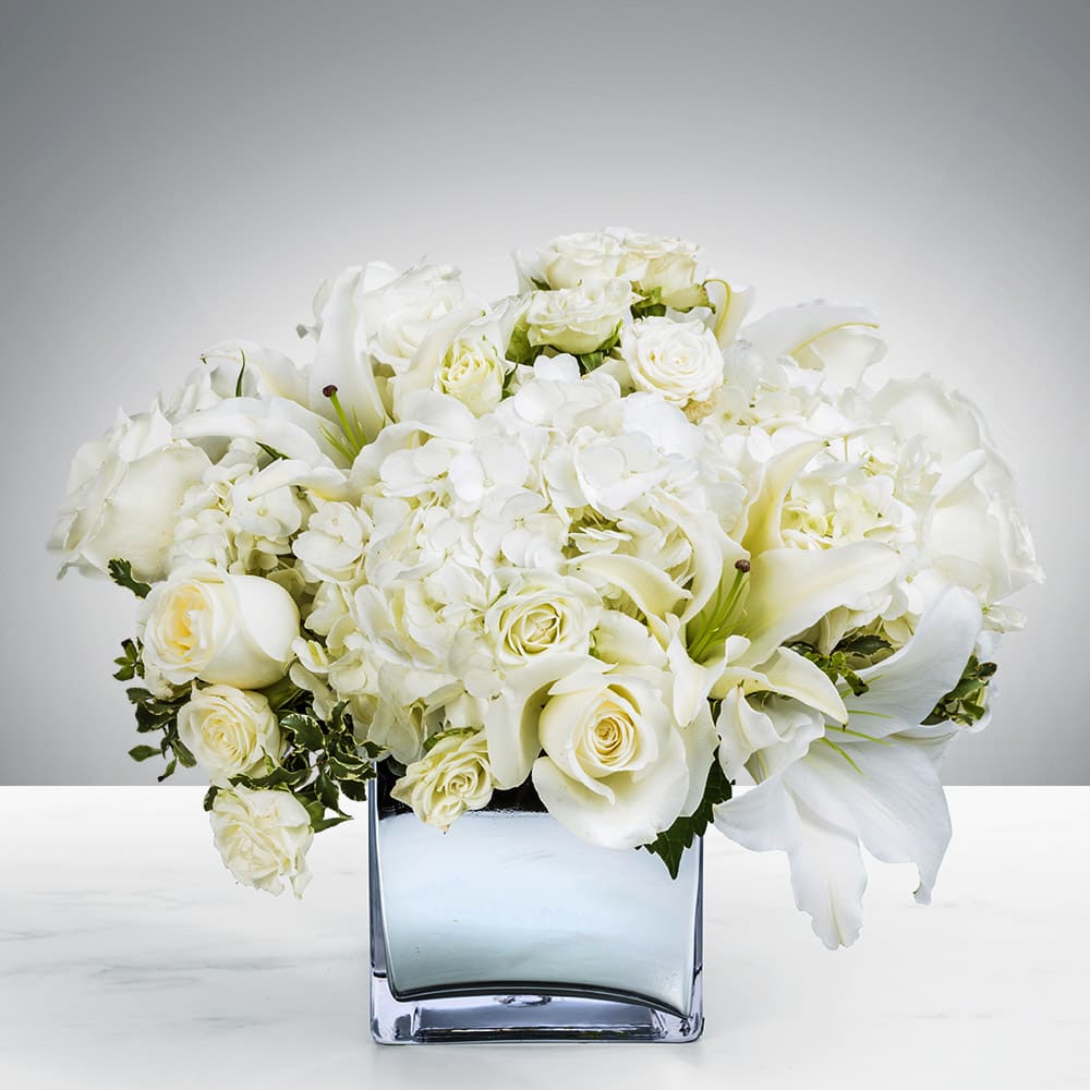 Snowy Field - White and silver is an elegant combination, indeed! Send this beautiful centerpiece style bouquet perfect for home or office. Designed with hydrangeas, roses and lilies arranged in a keepsake silver cube vase. Perfect for all occasions, birthday, anniversary, wedding, just because, to congratulate, say thank you and ofcouse, Mother's Day!  Approximately 10" D  