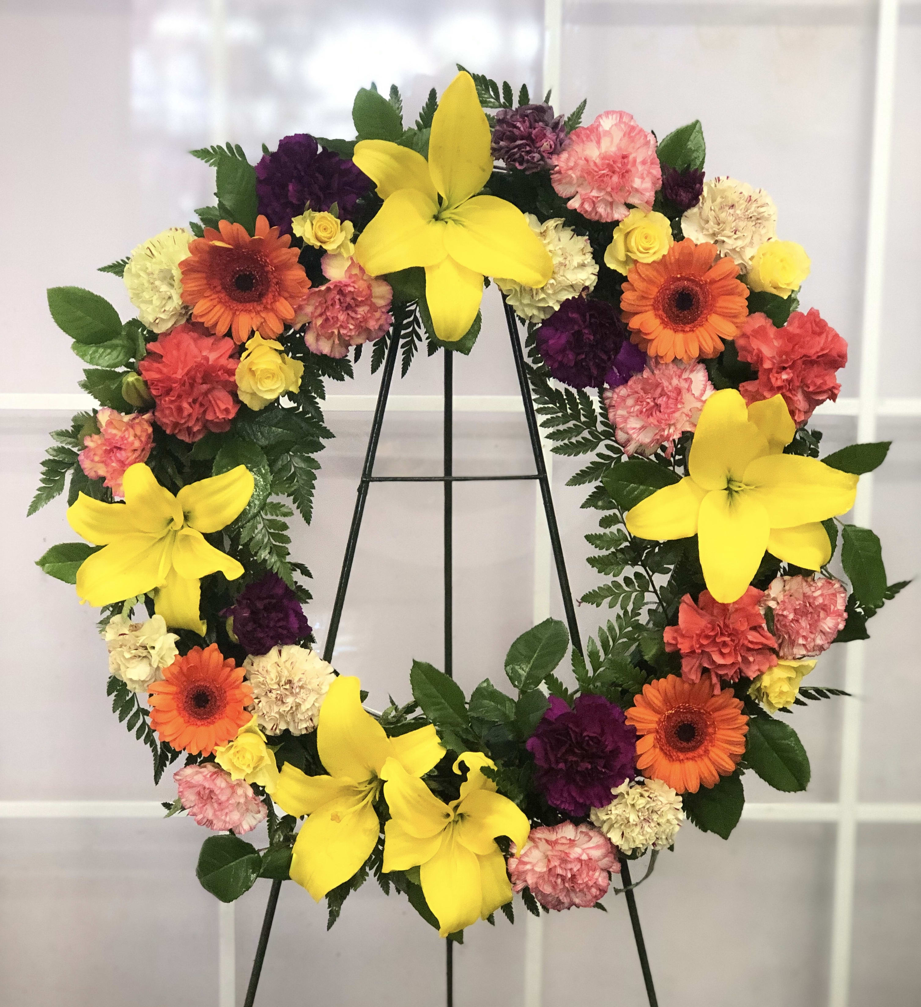 Heart-shaped floral wreath with yellow lilies, gerberas, and carnations