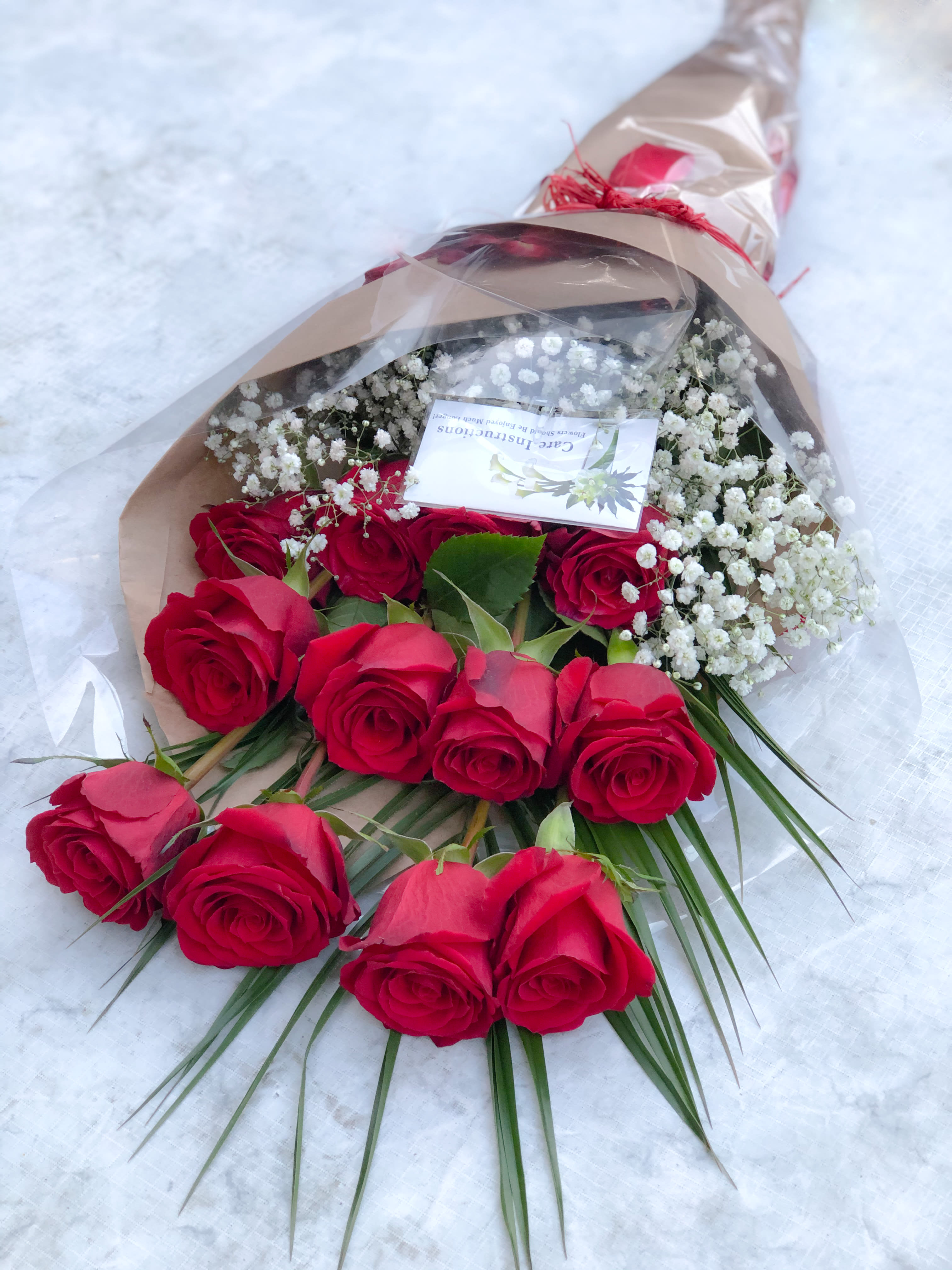 Bouquet of red roses with white baby's breath in brown paper