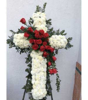 Floral cross made of white flowers with red roses and greenery
